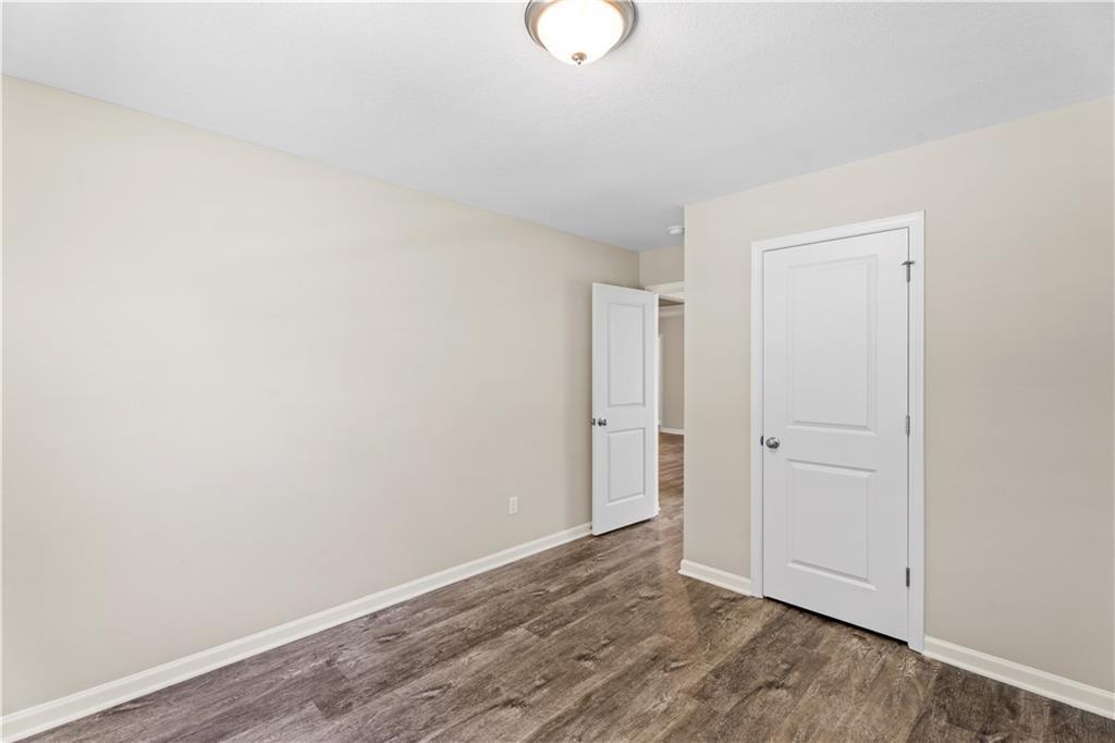 Bright secondary bedroom with beige walls, hardwood floors, and adjacent doorways in Davidson Homes The Washington, Phenix City