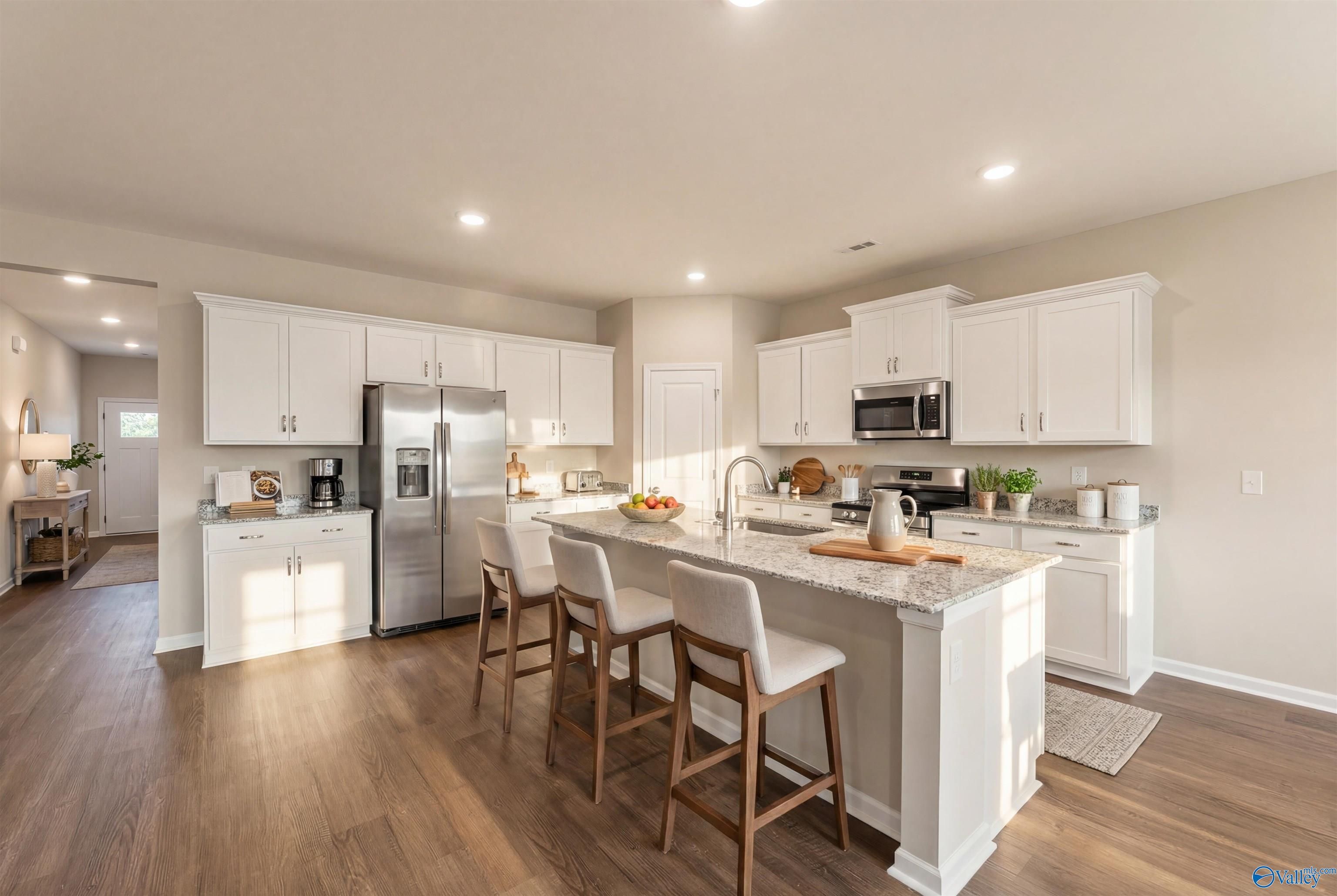 Modern white kitchen with large wood-top island, stainless appliances, and bar stools in Davidson Homes The Phoenix, Fayetteville, TN