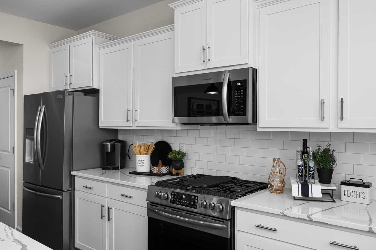 Modern kitchen in Wellers Knoll Lillington NC with white shaker cabinets, stainless steel appliances, subway tile backsplash