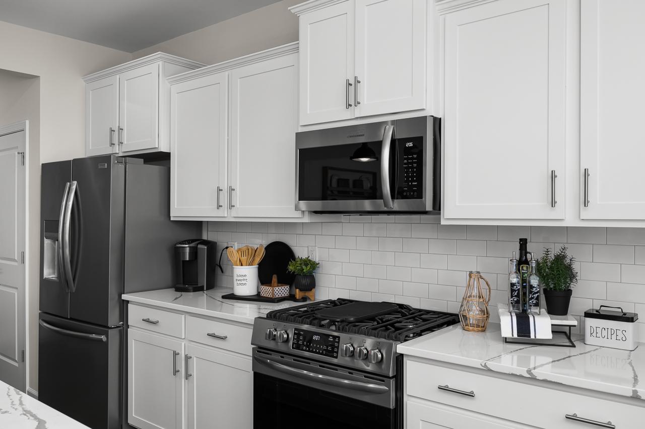 Modern kitchen in Wellers Knoll Lillington NC with white shaker cabinets, stainless steel appliances, subway tile backsplash