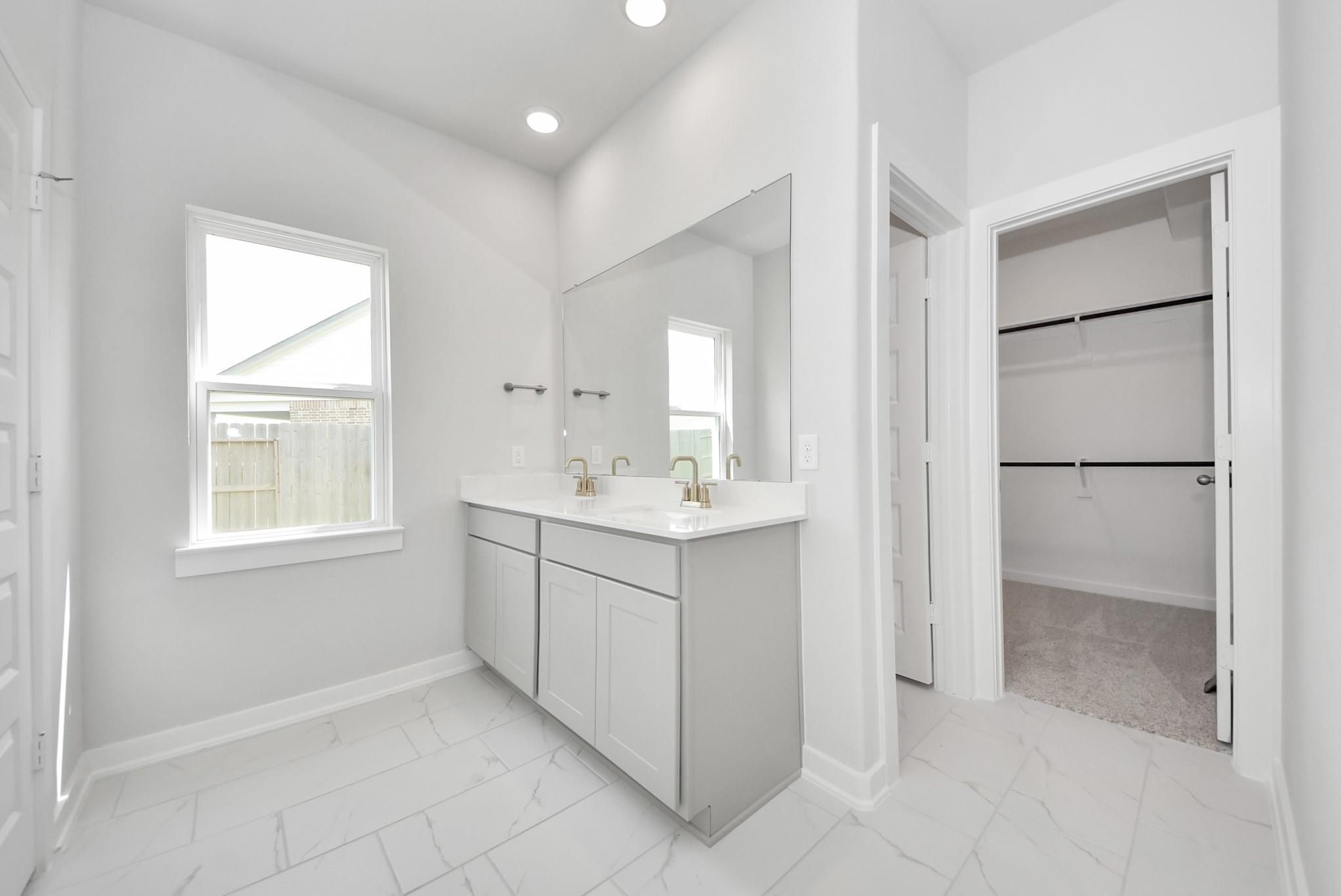Modern bathroom with dual vanity and walk-in closet in The Verano B floor plan by Davidson Homes in Sunterra, Katy, Texas.