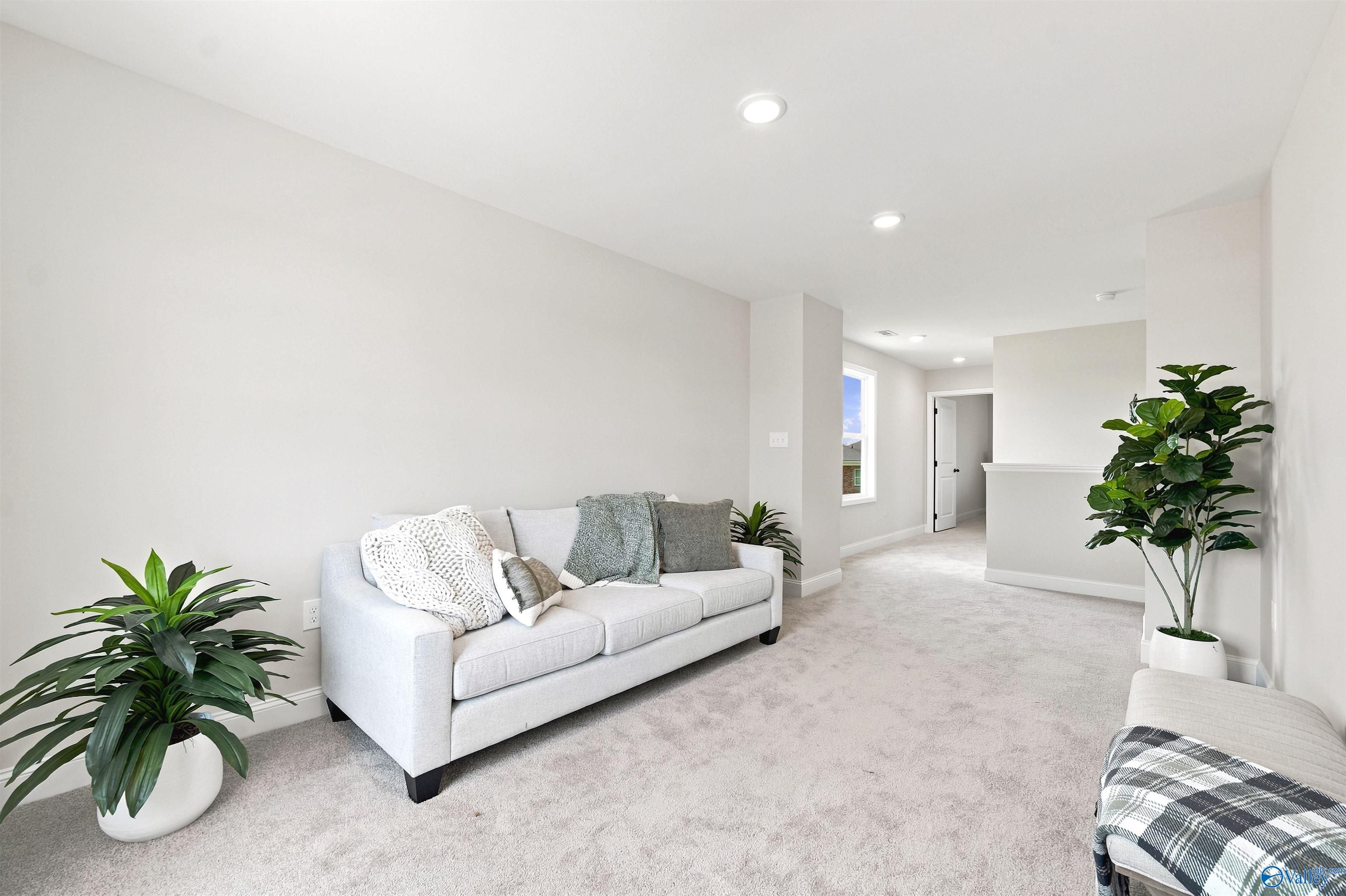 Bright upstairs loft with neutral carpet and sofa in The Burton B floor plan at Heritage Lakes, New Market, Alabama.