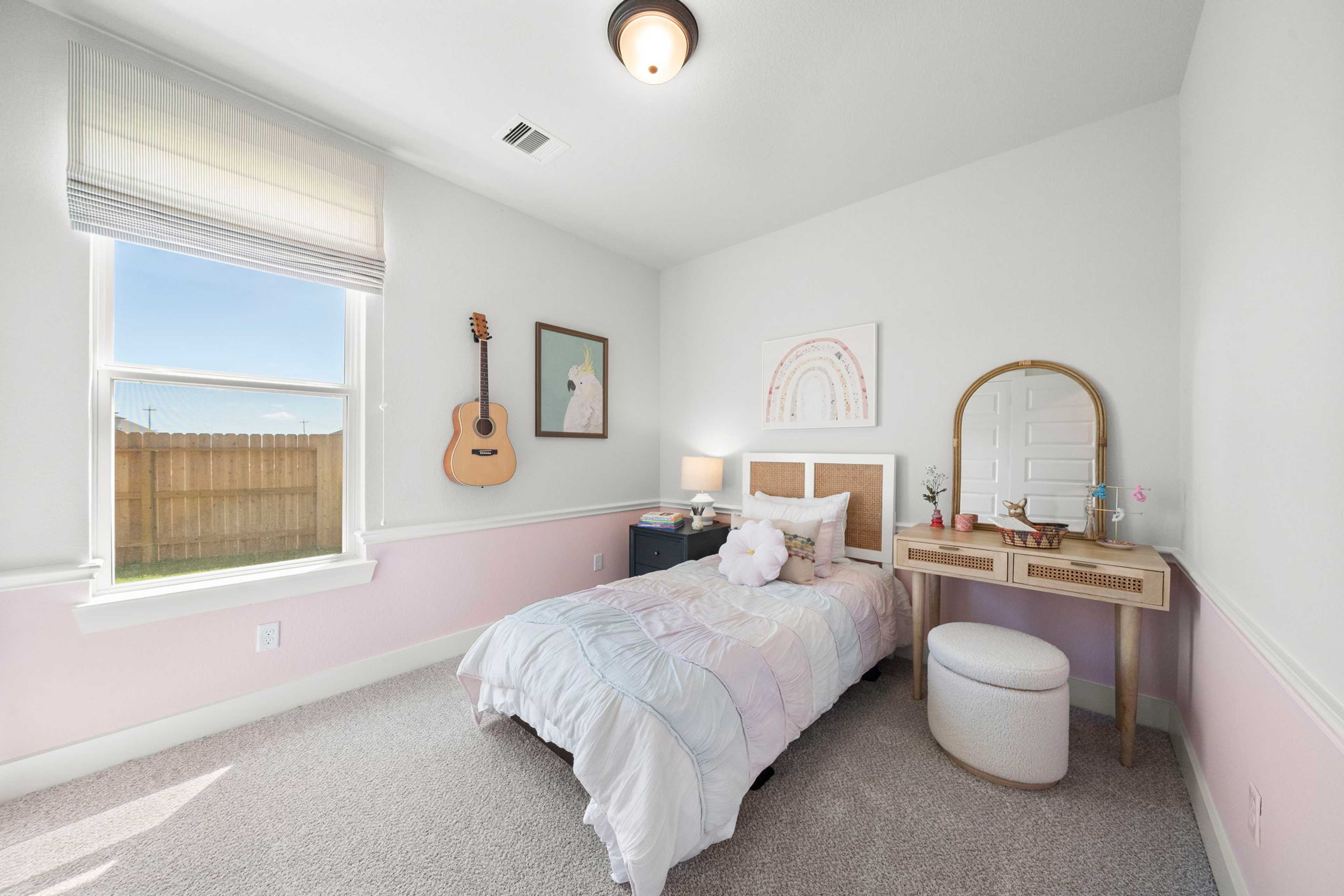 Cozy girl's bedroom in Lago Mar, Texas City TX by Davidson Homes featuring twin bed, woven vanity, wall guitar and rainbow art