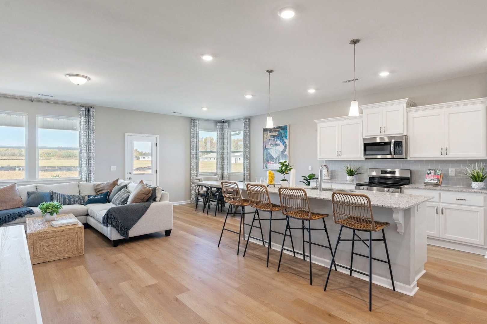 Spacious open-concept kitchen and living area in The Phoenix featuring white cabinets, large island with bar stools, and blue sectional sofa