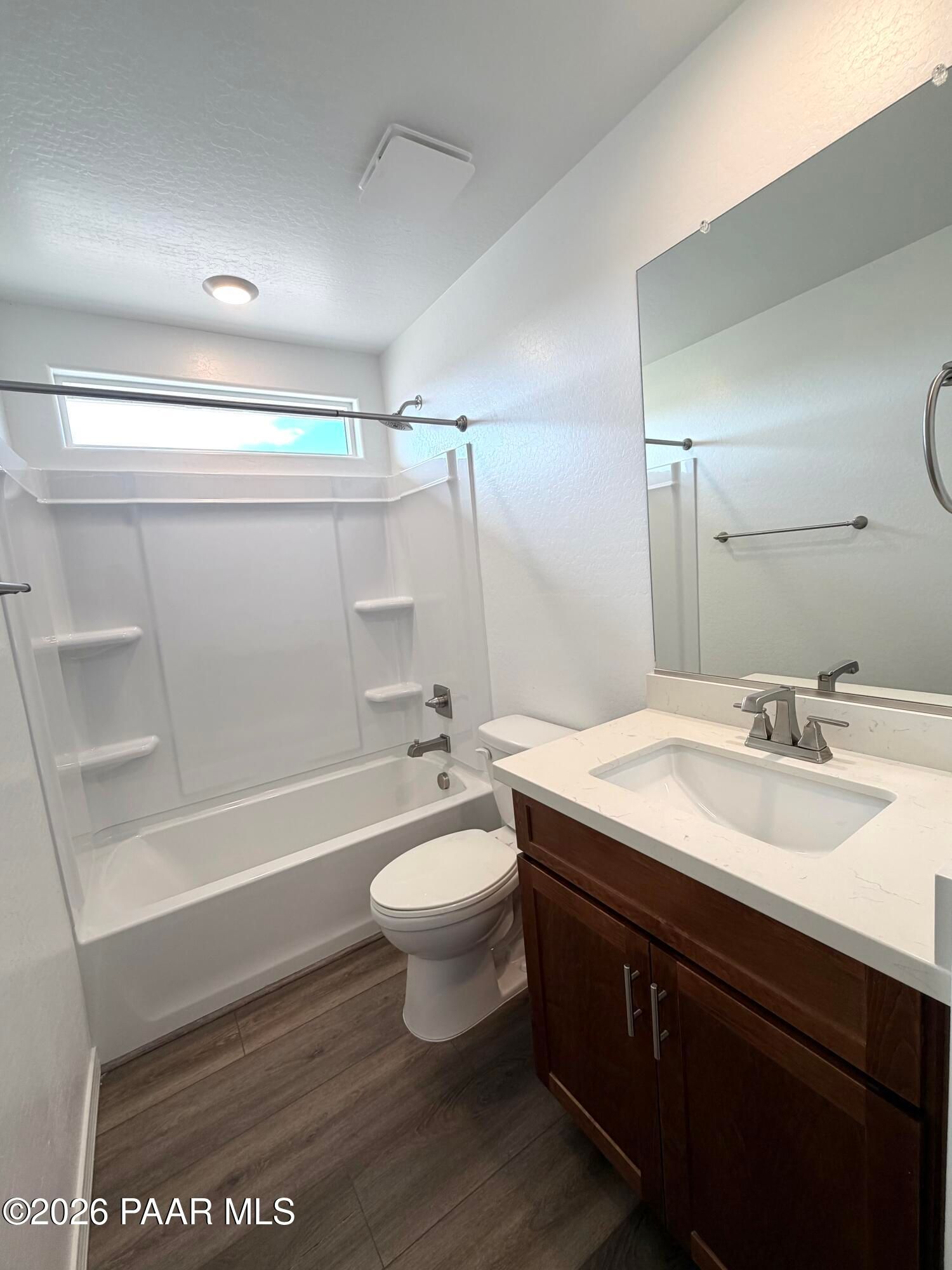Modern bathroom with vanity, tub-shower combo, and wood-style flooring in The Raleigh A home at South Ranch, Prescott.