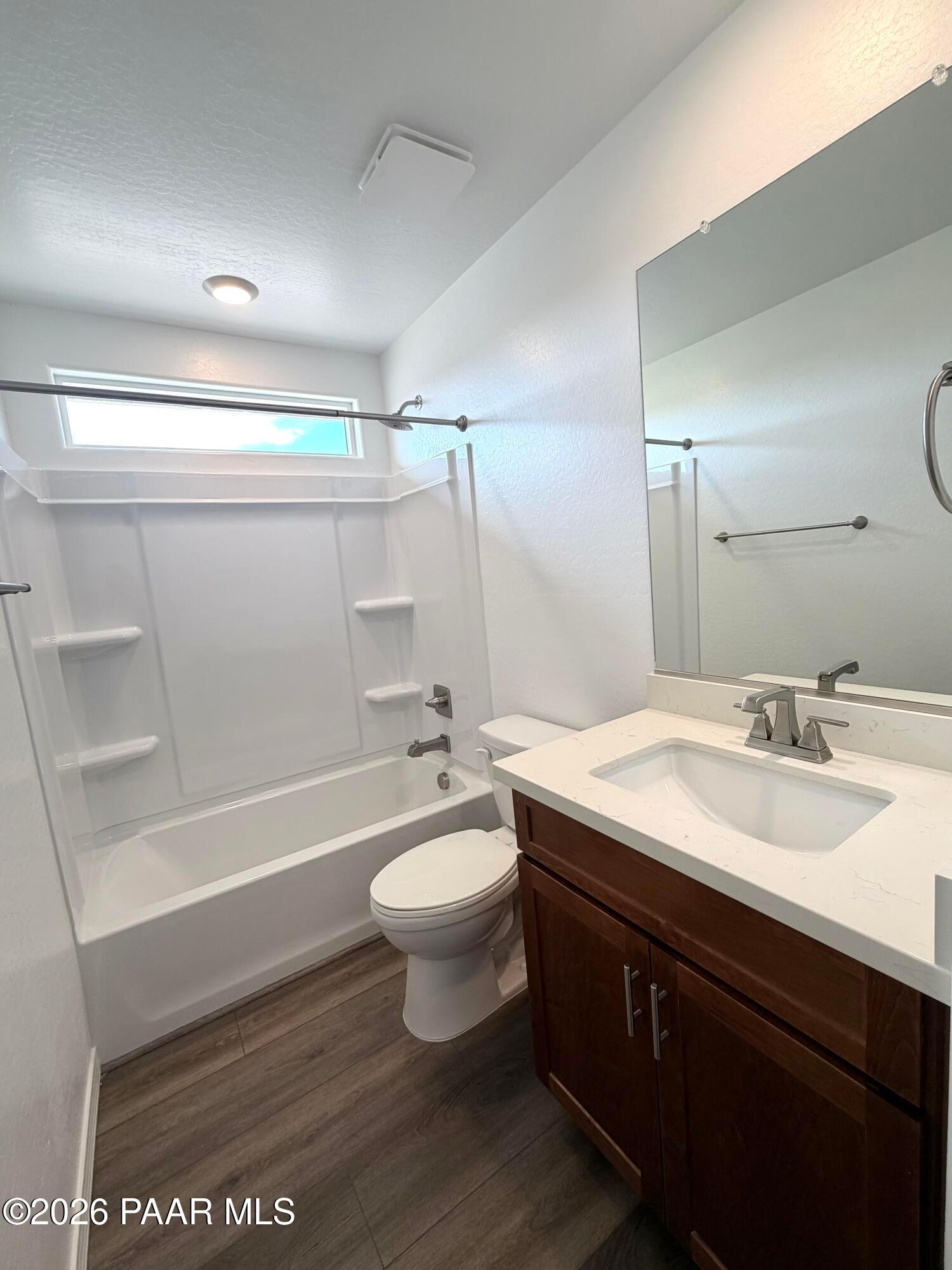 Modern bathroom with vanity, tub-shower combo, and wood-style flooring in The Raleigh A home at South Ranch, Prescott.