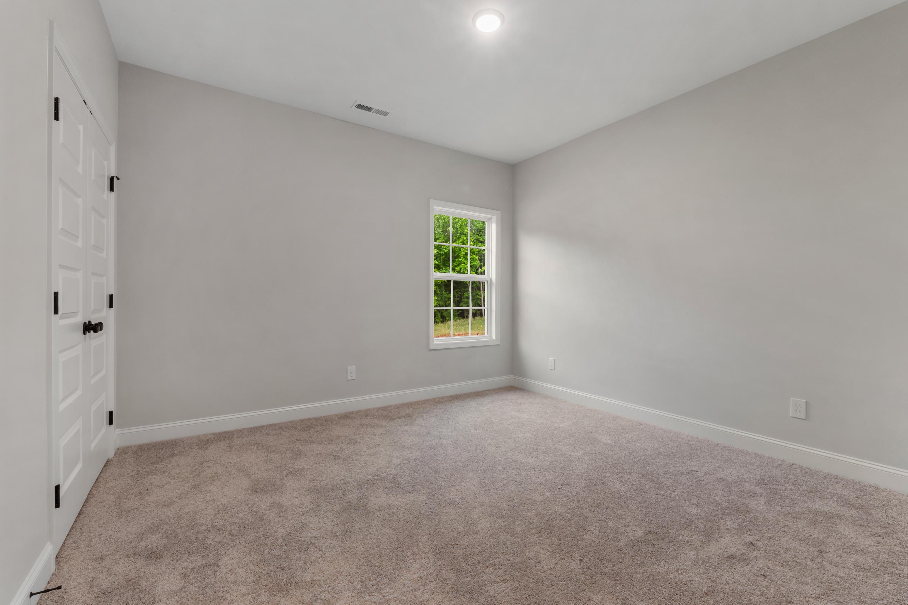 Spacious secondary bedroom in The Oxford home by Davidson Homes with gray walls, large window, carpet flooring, Meridianville AL