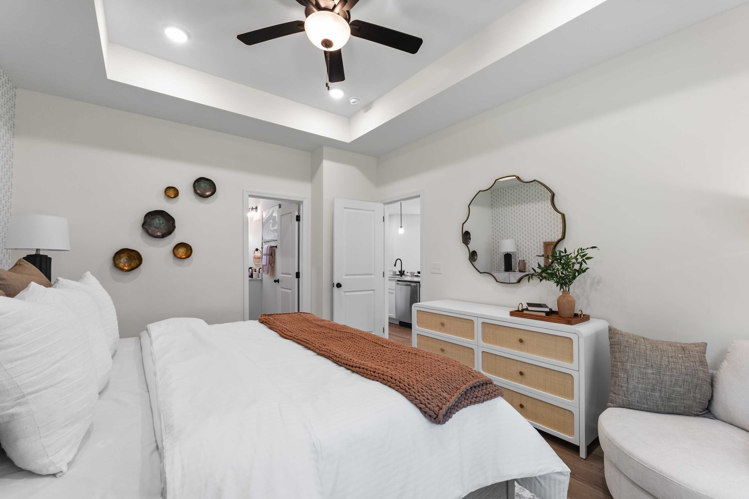 Spacious primary bedroom in Lynn Meadows Meridianville AL with king bed, ceiling fan, rattan mirror and en-suite bath
