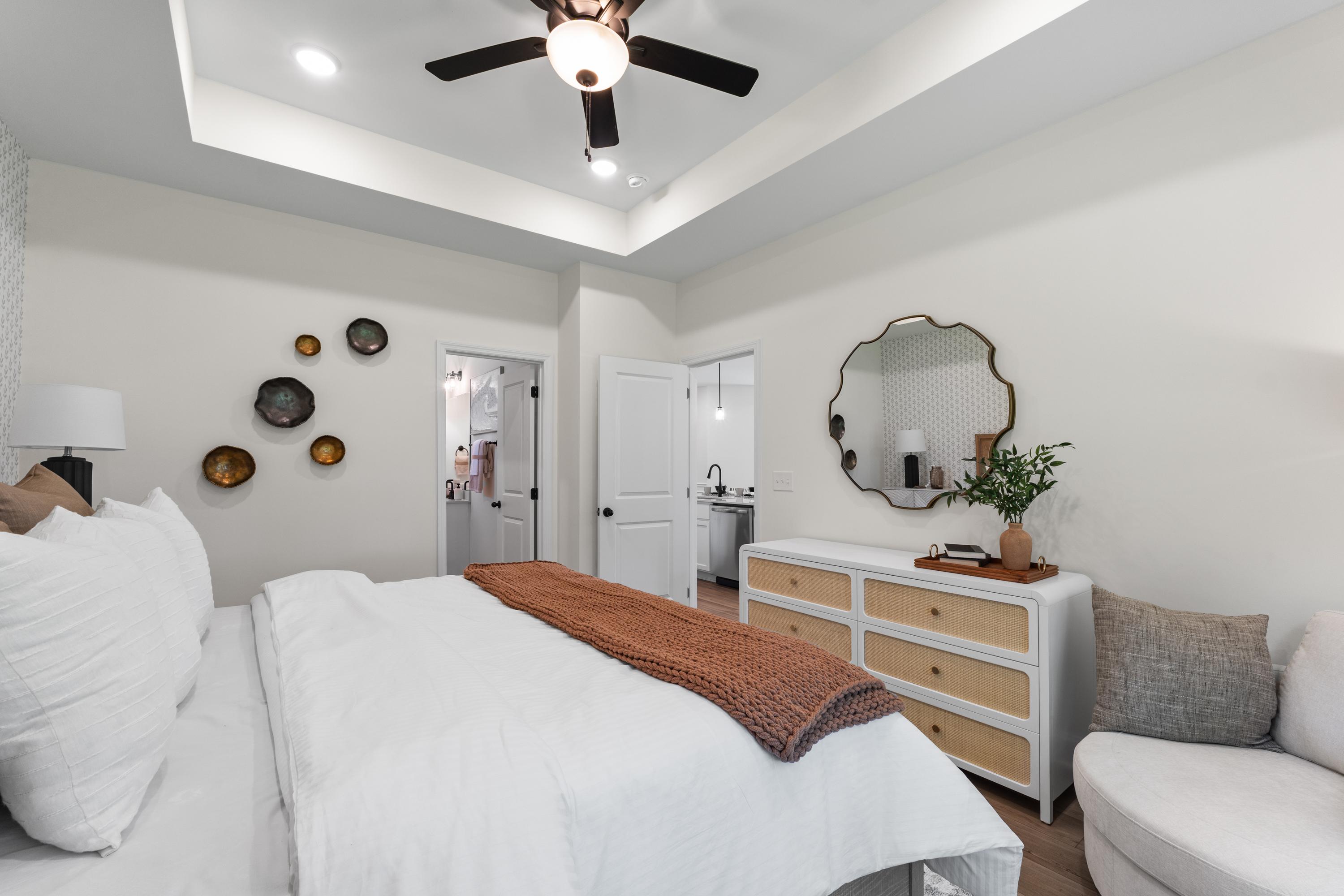 Spacious primary bedroom in Lynn Meadows Meridianville AL with king bed, ceiling fan, rattan mirror and en-suite bath