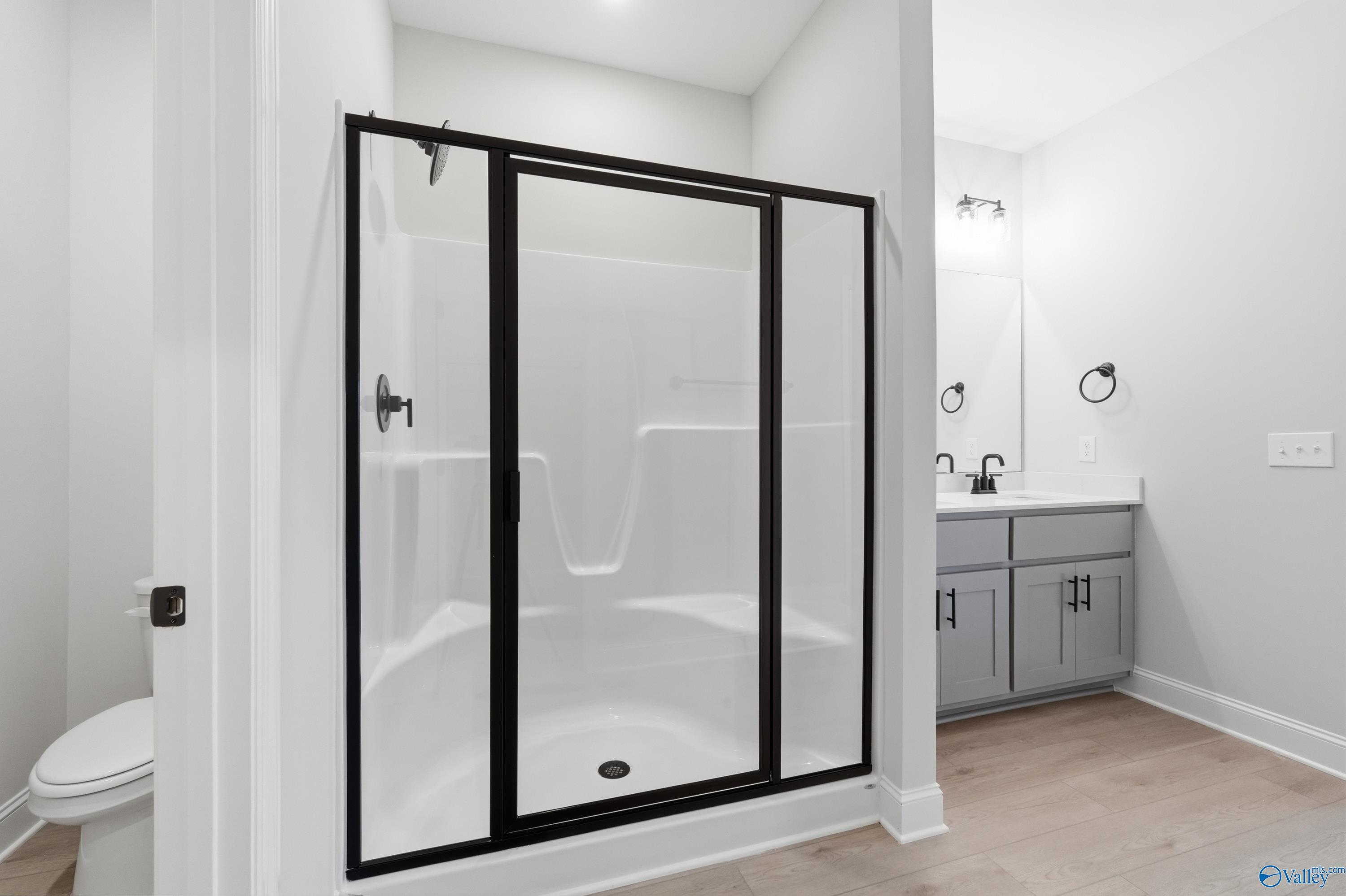 Modern bathroom with frameless glass shower, white subway tile, and grey vanity in Davidson Homes The Daphne C, Athens AL