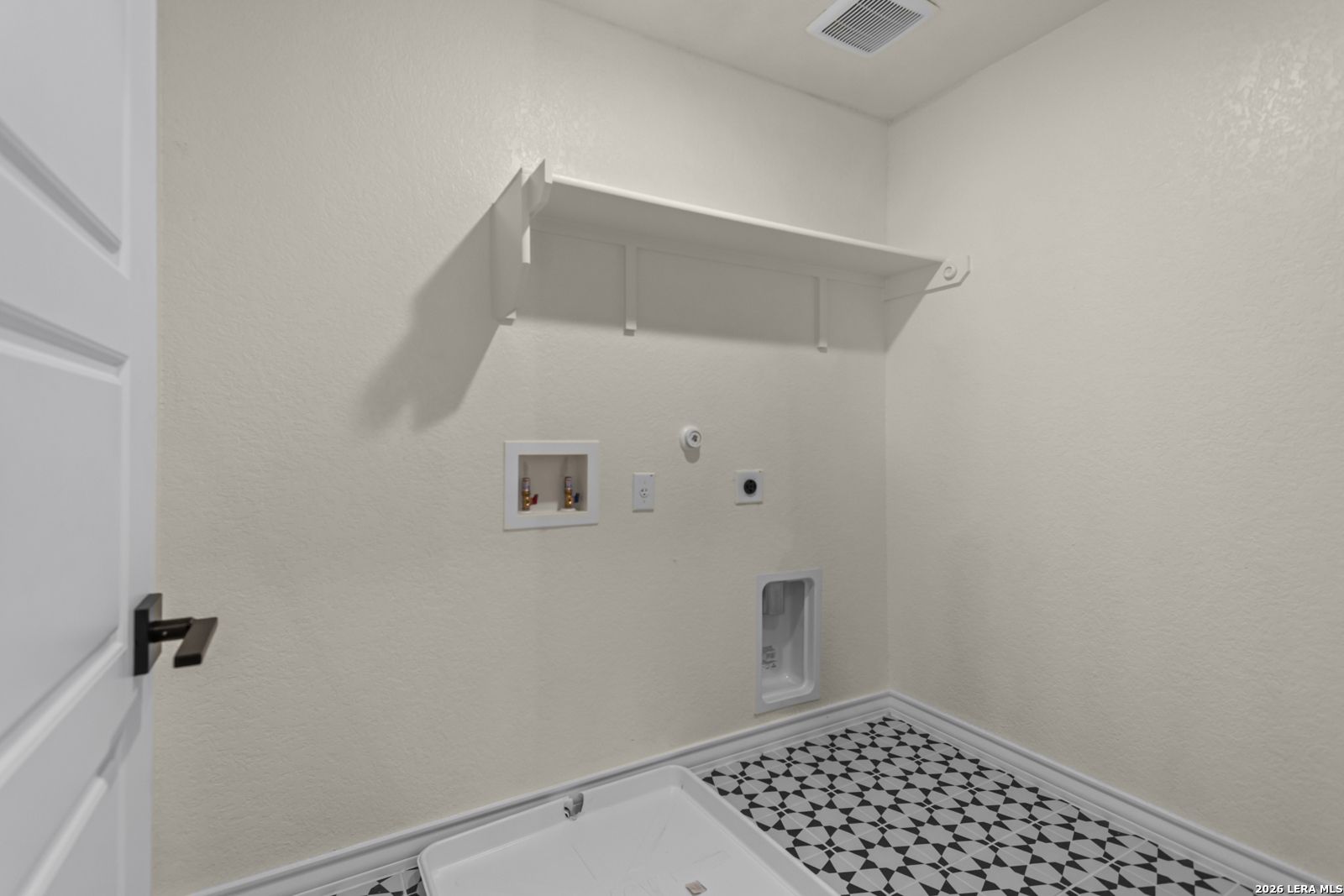 Laundry room with patterned tile floor, washer hookups, and shelving in The Danbury H home in Potranco Oaks, Castroville.