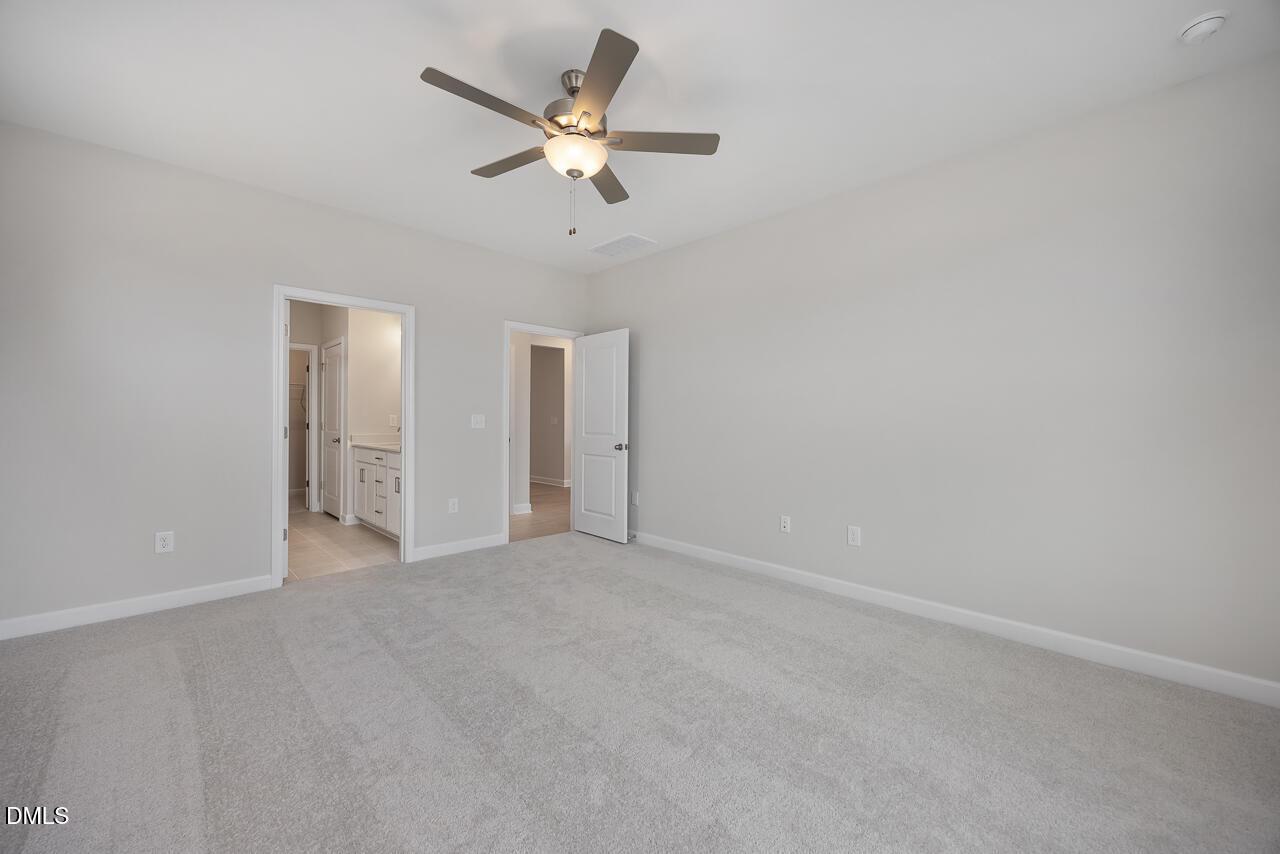 Spacious master bedroom with ceiling fan, gray walls, carpet flooring, and en-suite bath in Davidson Homes The Daphne C, Lillington, NC
