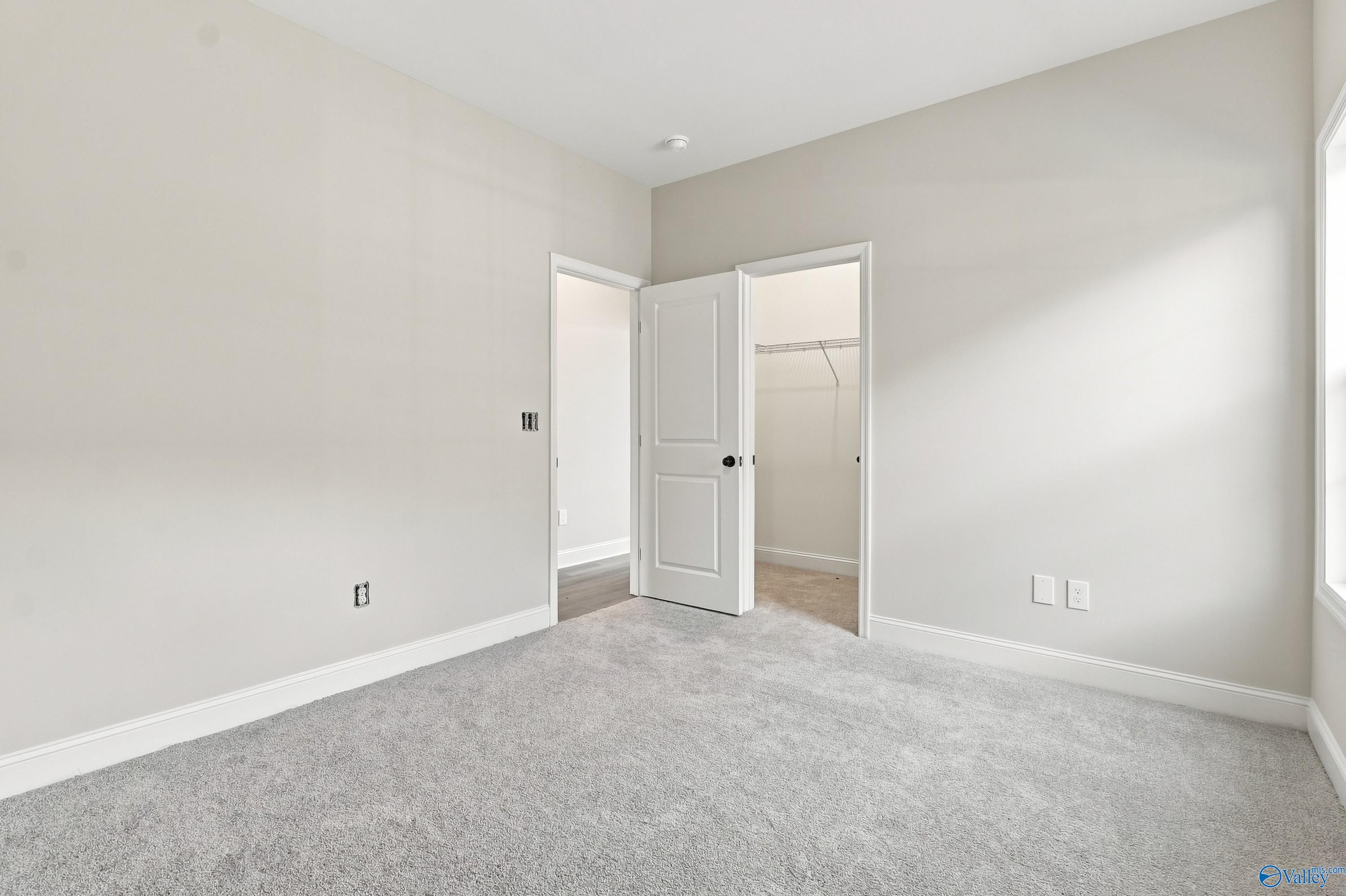 Spacious bedroom with neutral carpet and walk-in closet in The Rockford B floor plan at Kendall Downs, Toney, Alabama.