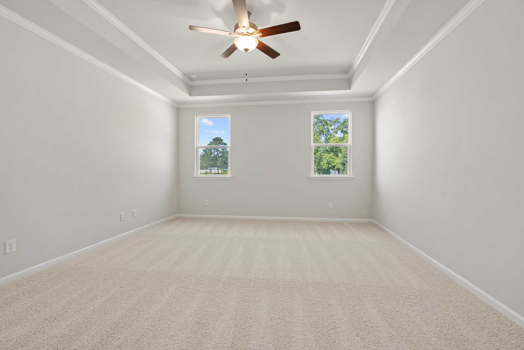 Spacious bedroom at Everleigh in Locust Grove GA by Davidson Homes with ceiling fan, neutral walls, carpet floors and large windows