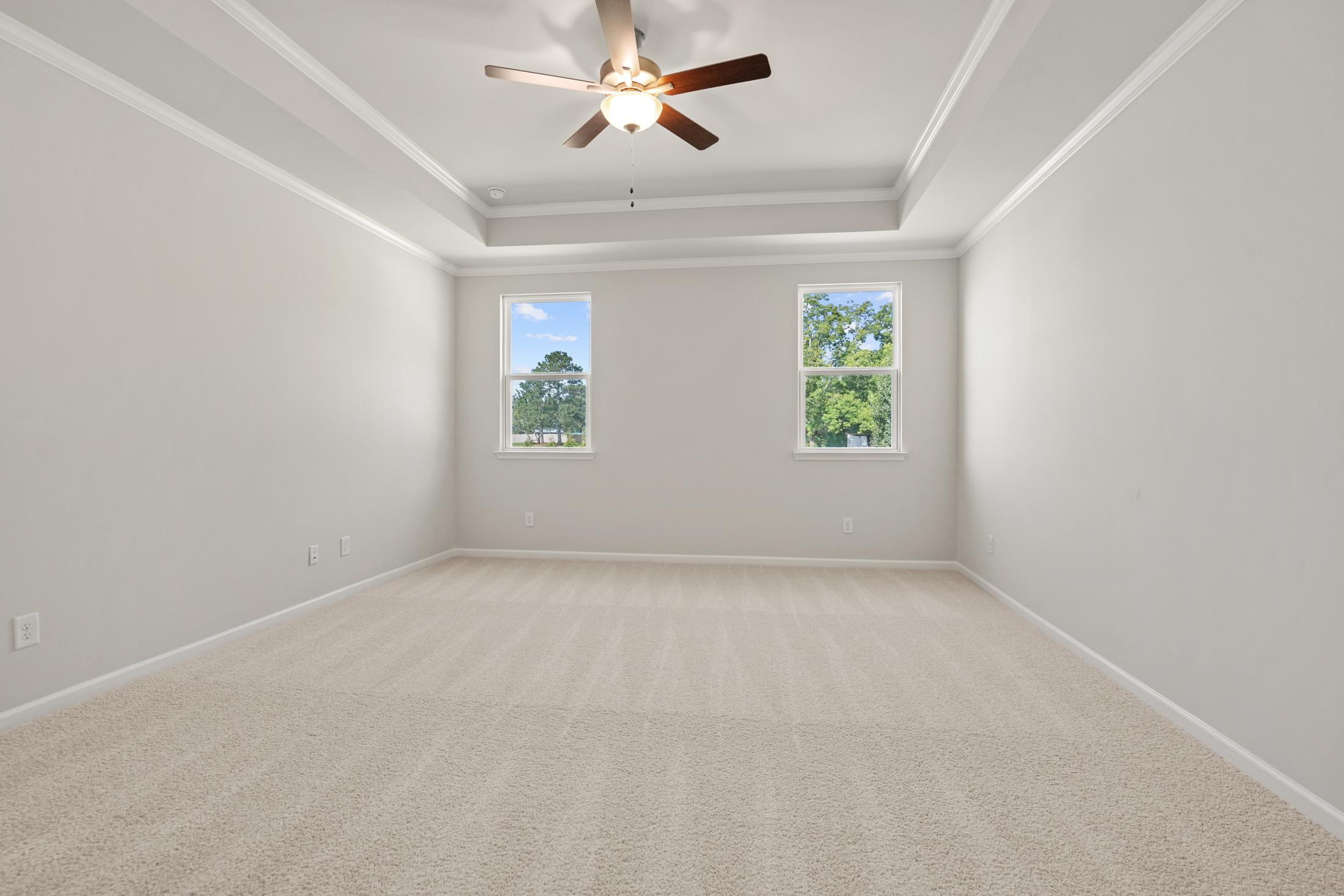 Spacious bedroom at Everleigh in Locust Grove GA by Davidson Homes with ceiling fan, neutral walls, carpet floors and large windows