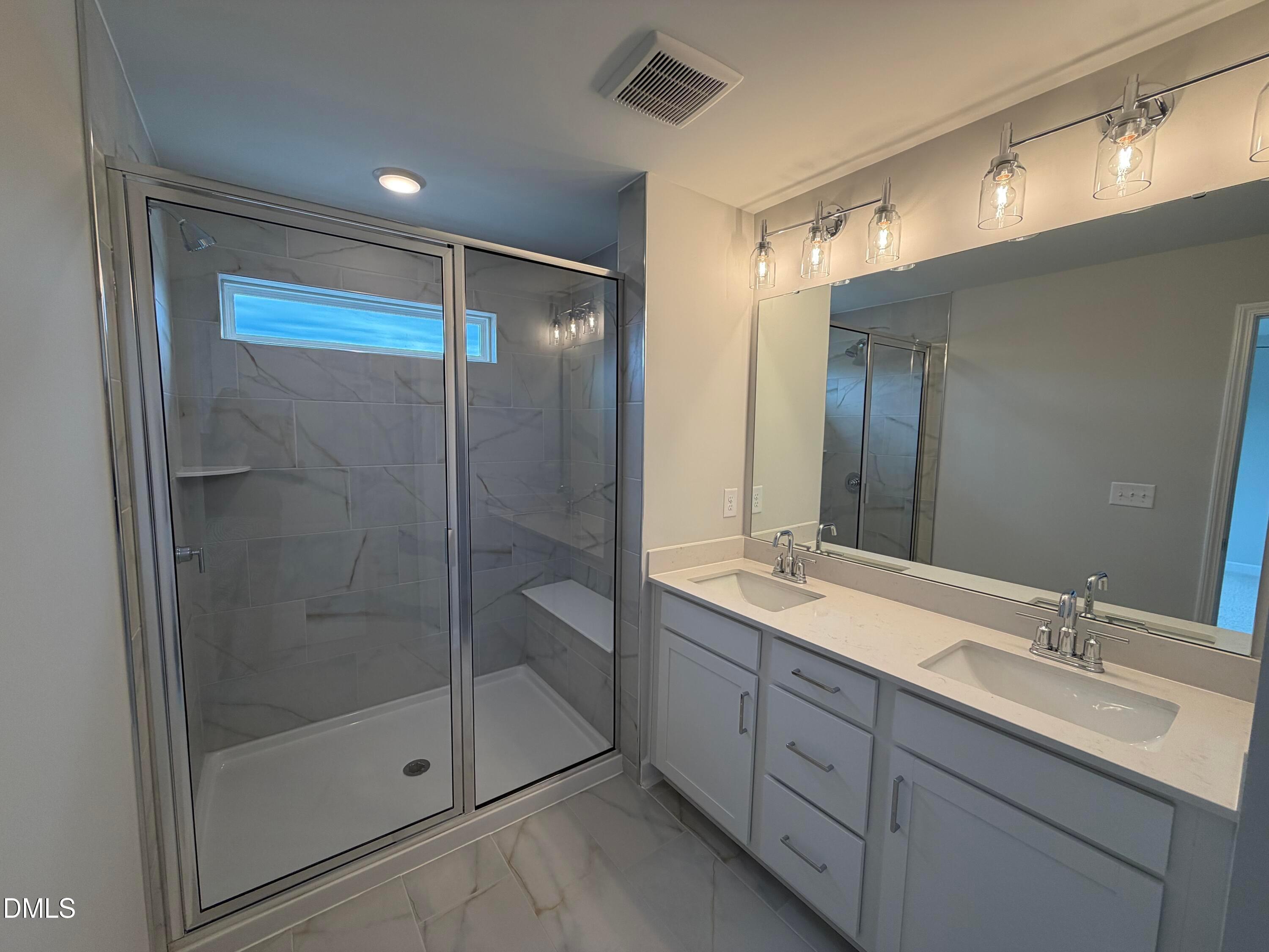 Modern master bathroom featuring glass shower with marble tiles, double vanity, quartz counters in Davidson Homes The Mitchell, Knightdale, NC
