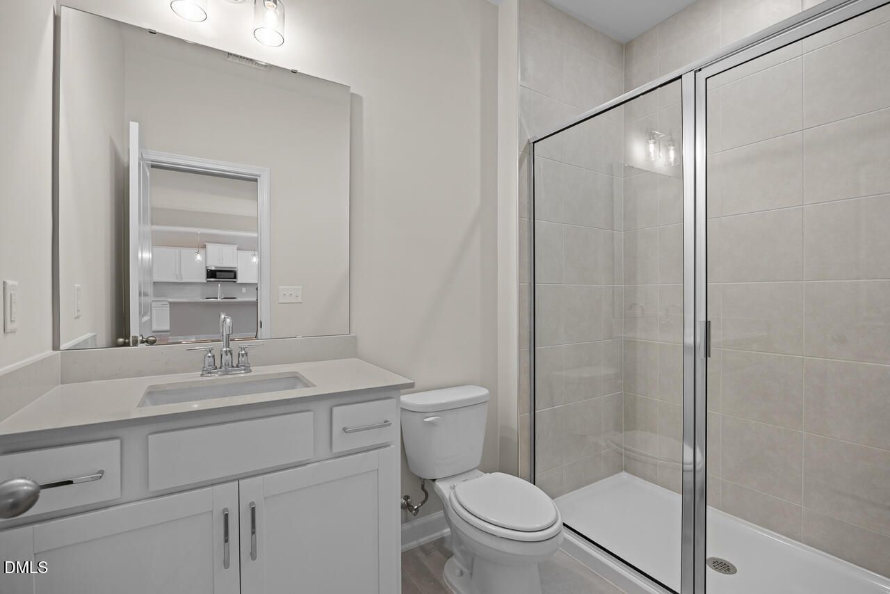 Modern bathroom with white vanity, glass walk-in shower, and tile surround in Davidson Homes The Willow C, Zebulon, NC