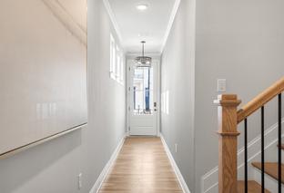 Spacious entry hallway in The Washington H townhome with oak staircase, chandelier, hardwood floors, and gray walls