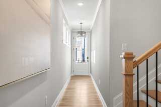 Spacious entry hallway in The Washington H townhome with oak staircase, chandelier, hardwood floors, and gray walls