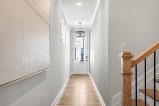 Spacious entry hallway in The Washington H townhome with oak staircase, chandelier, hardwood floors, and gray walls