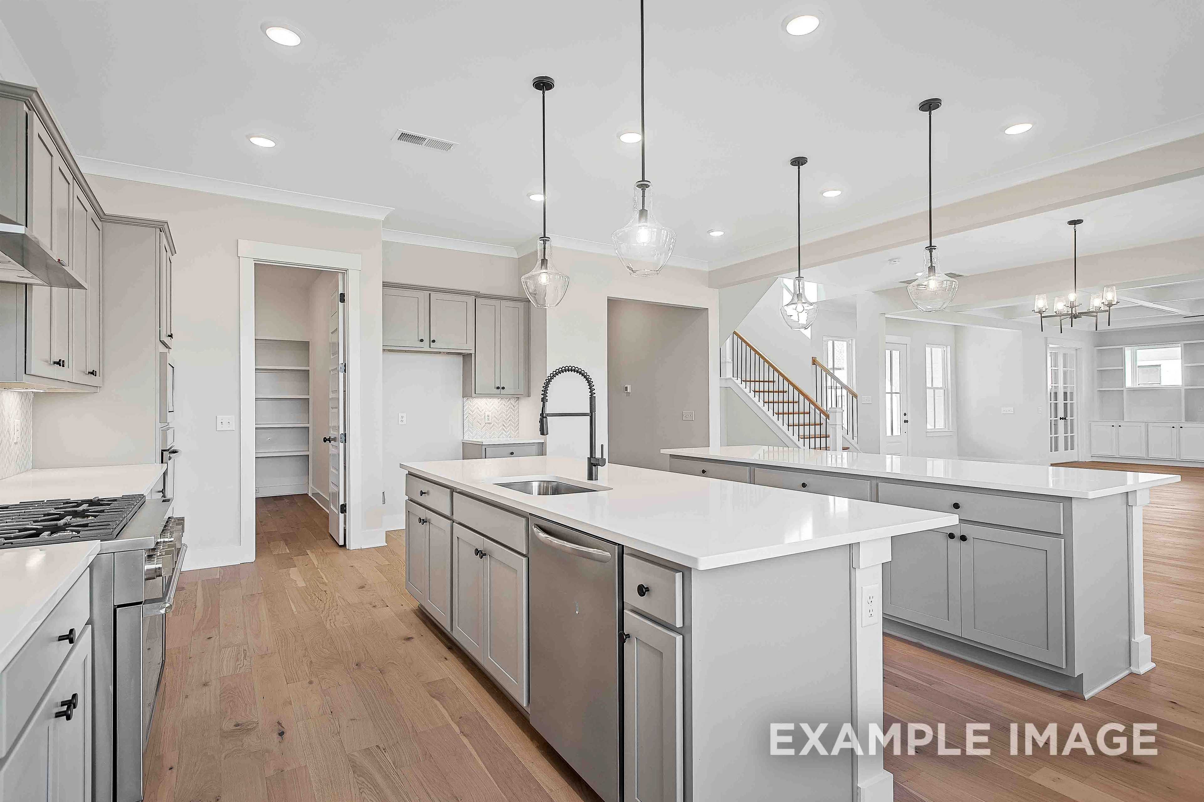 Spacious open-concept kitchen in The Alston A by Davidson Homes, gray shaker cabinets, white quartz island, stainless appliances, hardwood floors