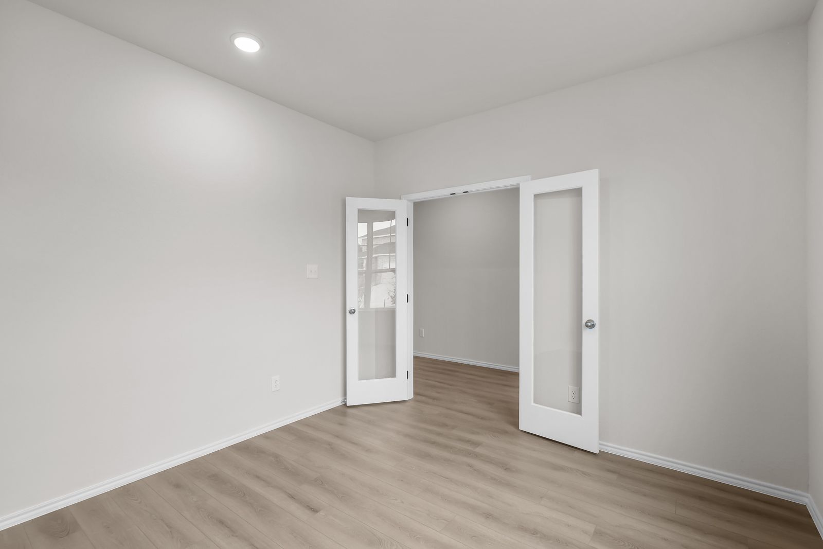 Flexible study or home office space in The Sequoia C featuring elegant French doors and modern wood-style flooring.