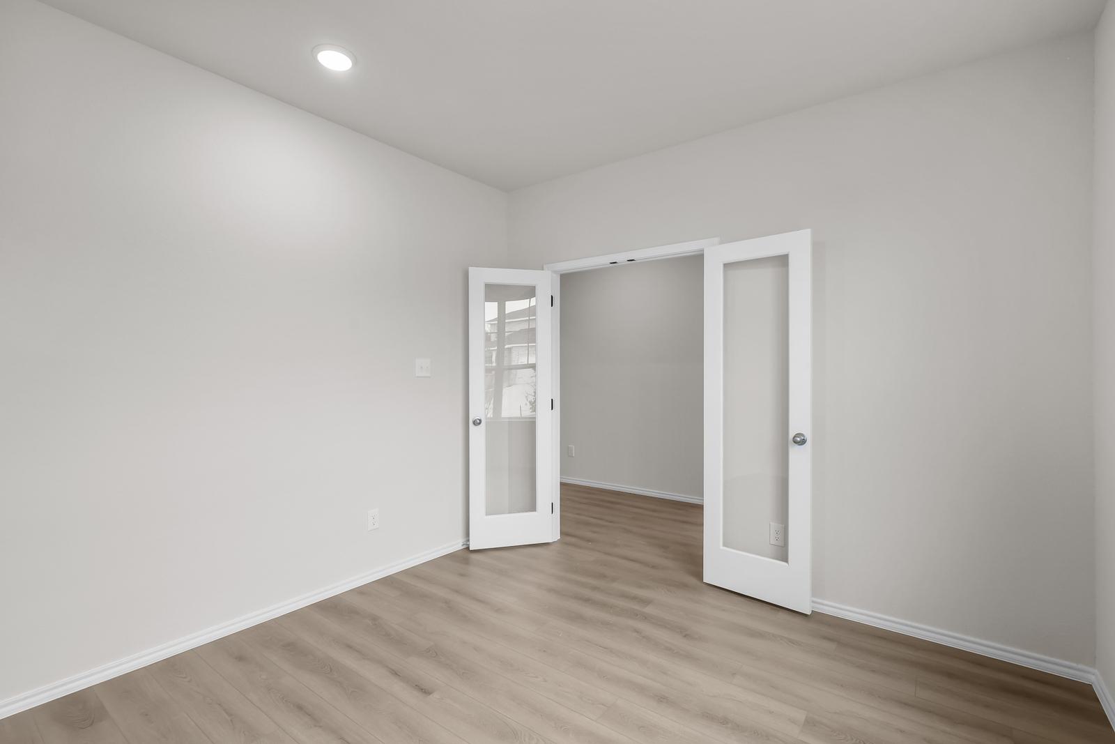 Flexible study or home office space in The Sequoia C featuring elegant French doors and modern wood-style flooring.
