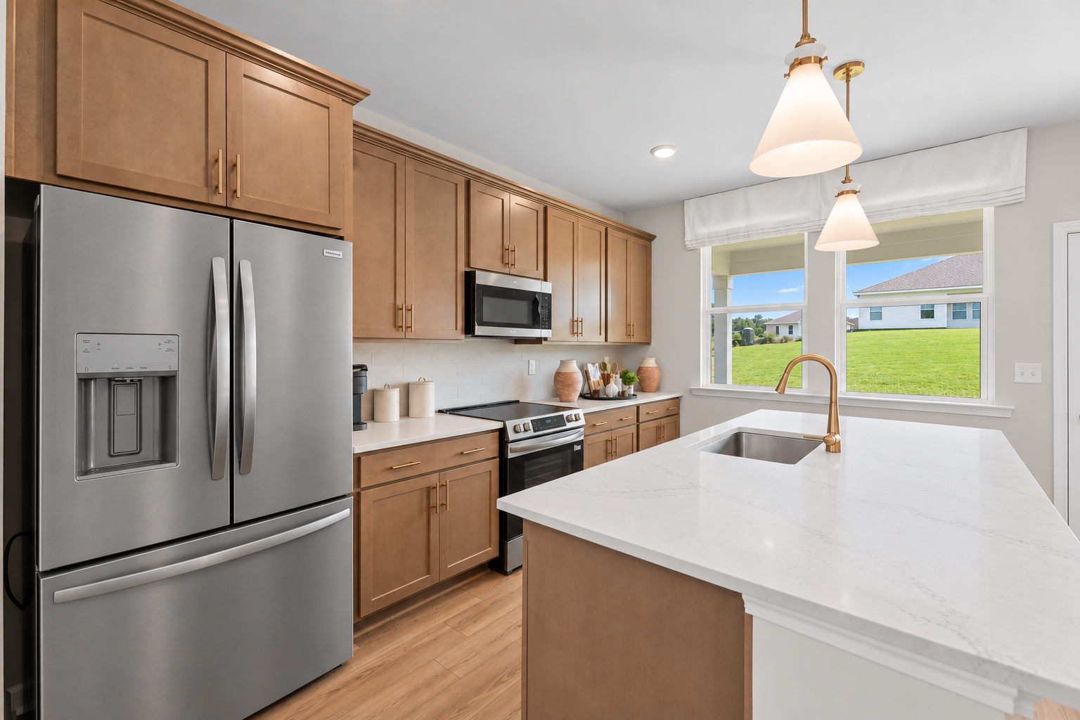 Modern kitchen at Donahue Ridge in Auburn, Alabama with wood cabinets, white quartz island, and stainless steel appliances by Davidson Homes