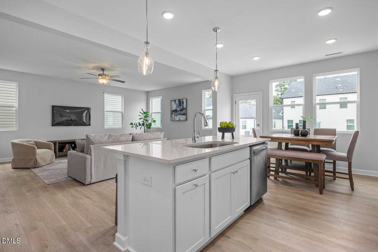 Open-concept kitchen with white island sink, dining table, and living room sofa in Davidson Homes The Gavin B, Lillington, NC