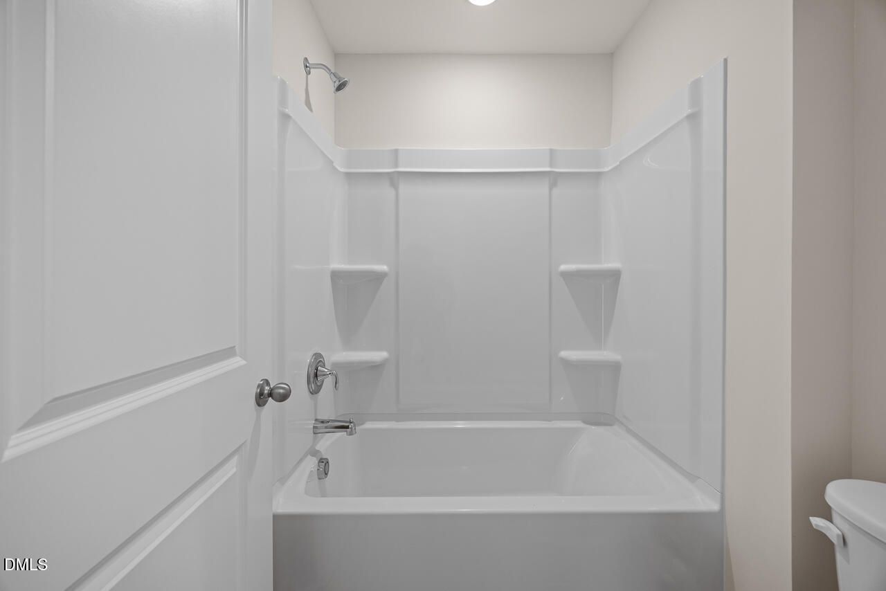 White tub and shower combo with corner shelves in full bath of Davidson Homes The Mitchell floor plan, Knightdale, NC