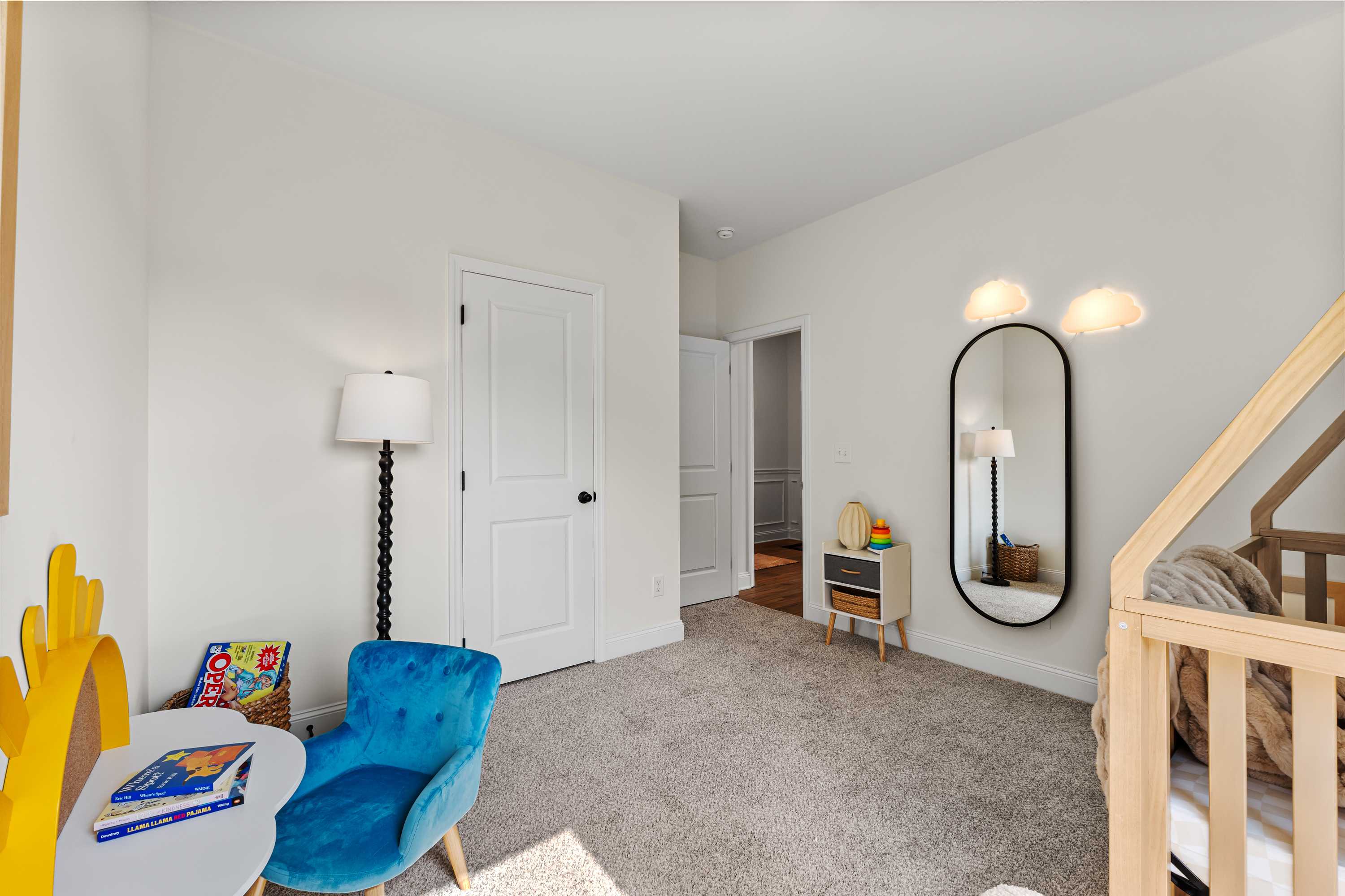 Cozy children's bedroom in Lynn Meadows, Meridianville, Alabama with wooden playhouse bed, blue velvet chair, and storybooks