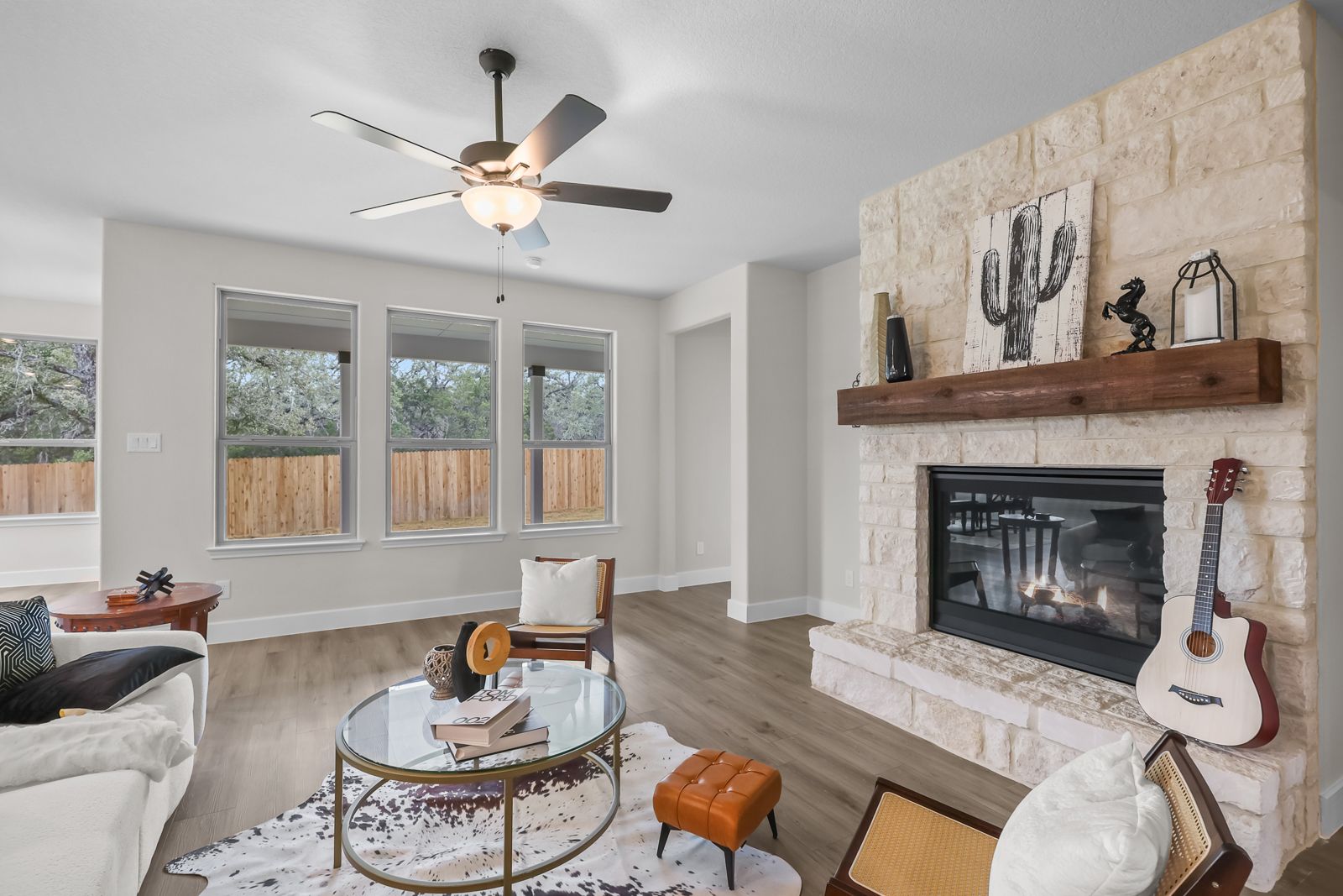 Spacious living room in The Belmont by Davidson Homes featuring a stone fireplace, wood floors, and modern interior decor.