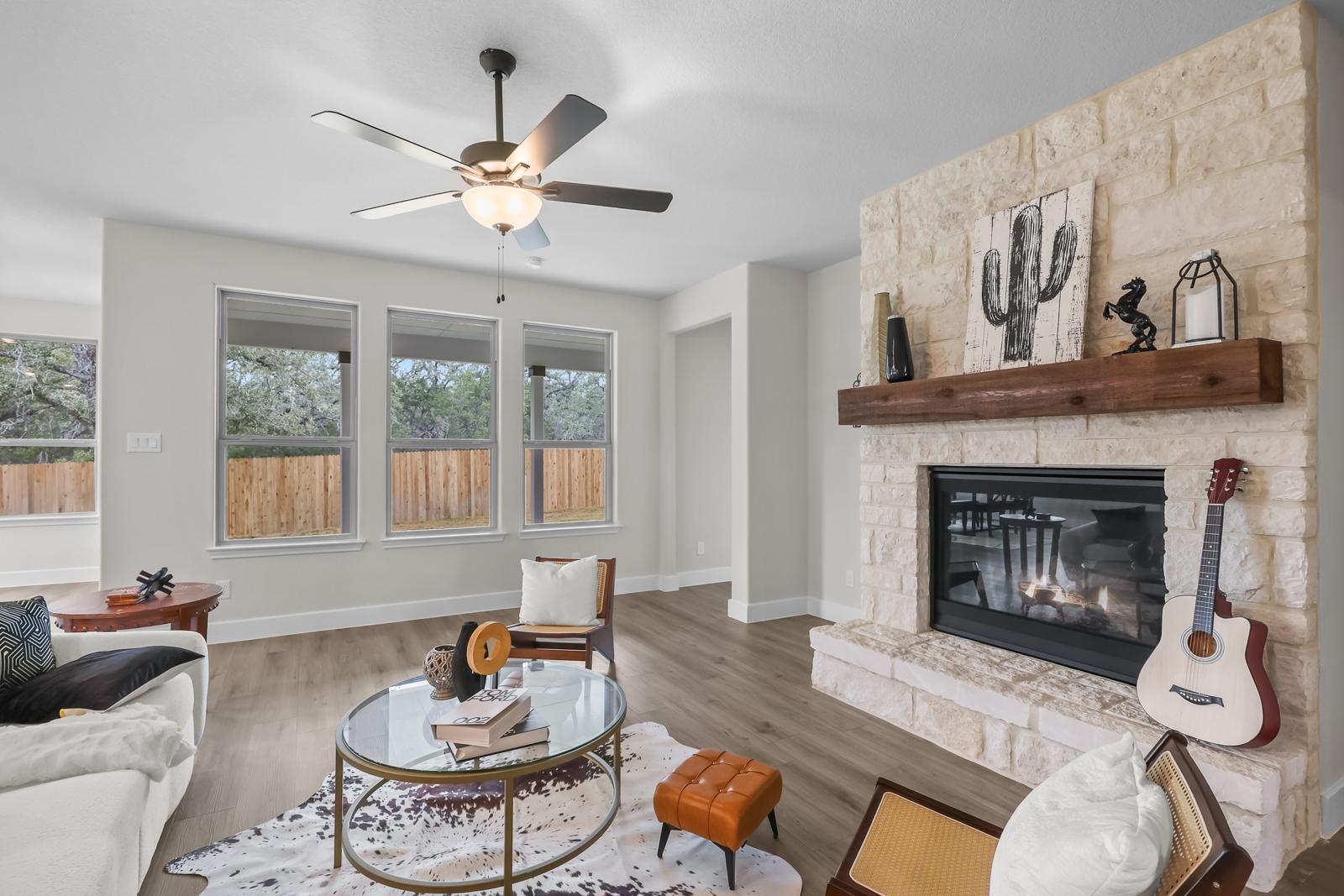 Spacious living room in The Belmont by Davidson Homes featuring a stone fireplace, wood floors, and modern interior decor.