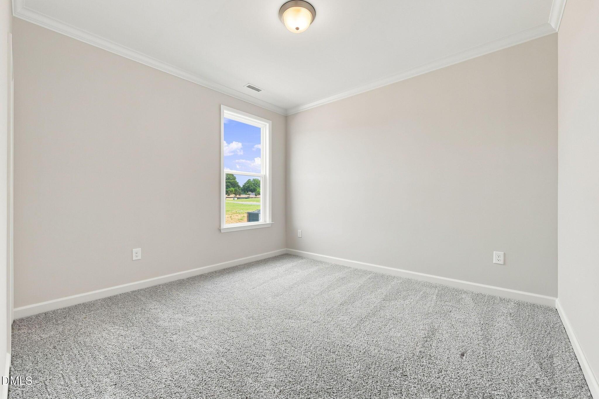 Bright, carpeted bedroom with neutral walls in The Magnolia B floor plan at Retreat at North Main, Lillington, NC.