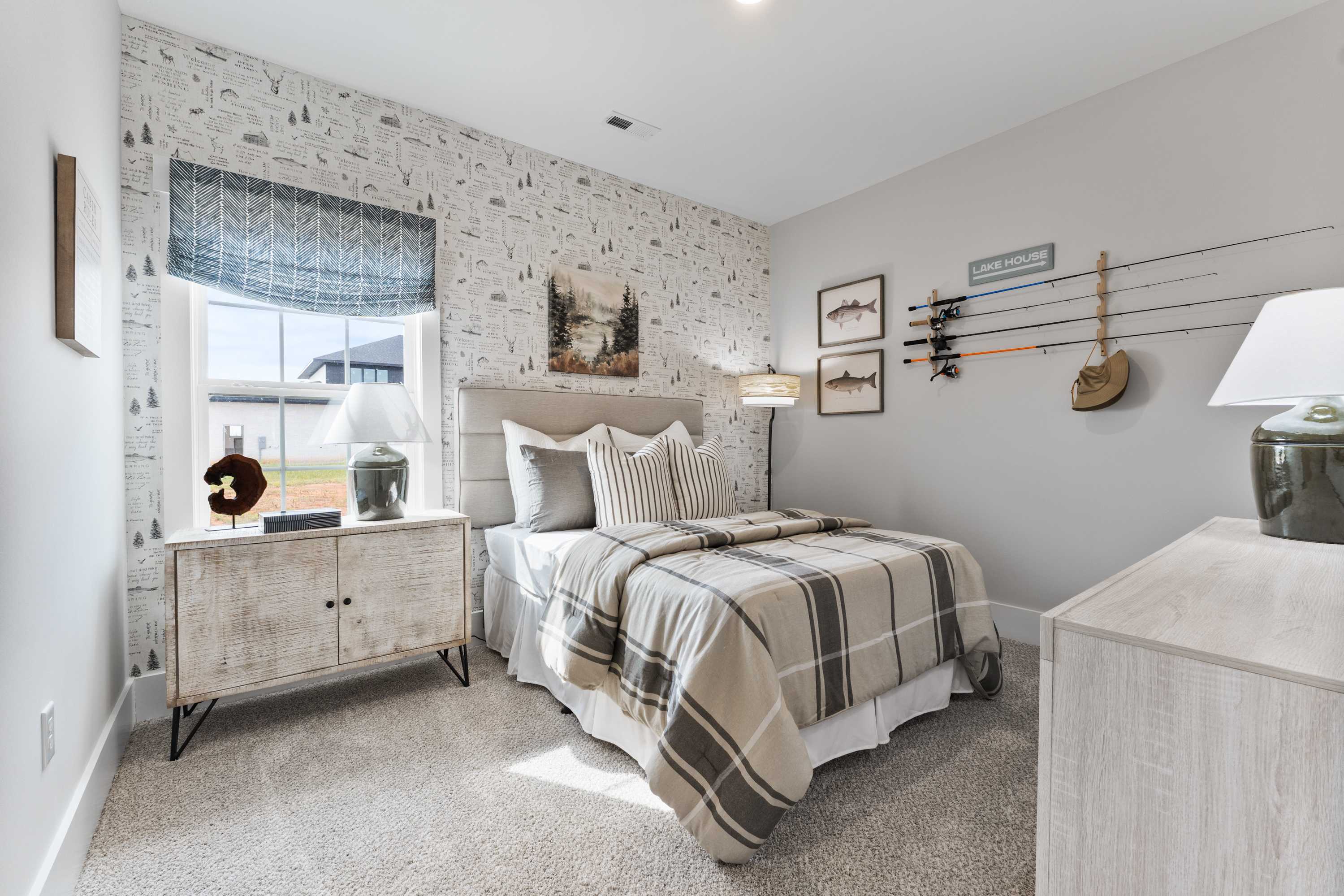 Cozy bedroom at River Road Estates in Decatur Alabama with adventure-themed wallpaper, plaid bedding, and fishing rod rack