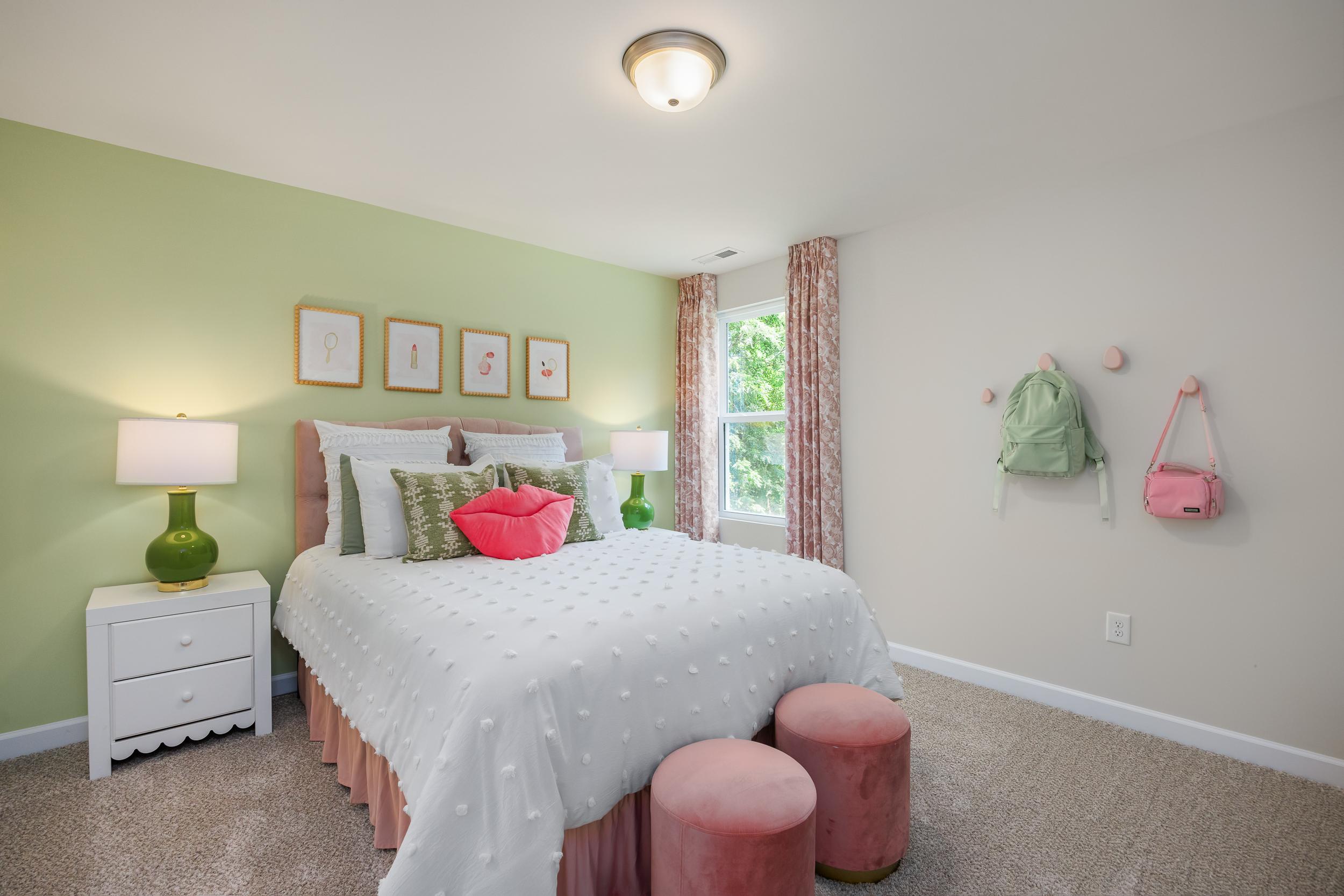 Charming girl's bedroom at Retreat at North Main in Lillington NC featuring green walls, pink accents, cozy white bed and window seat