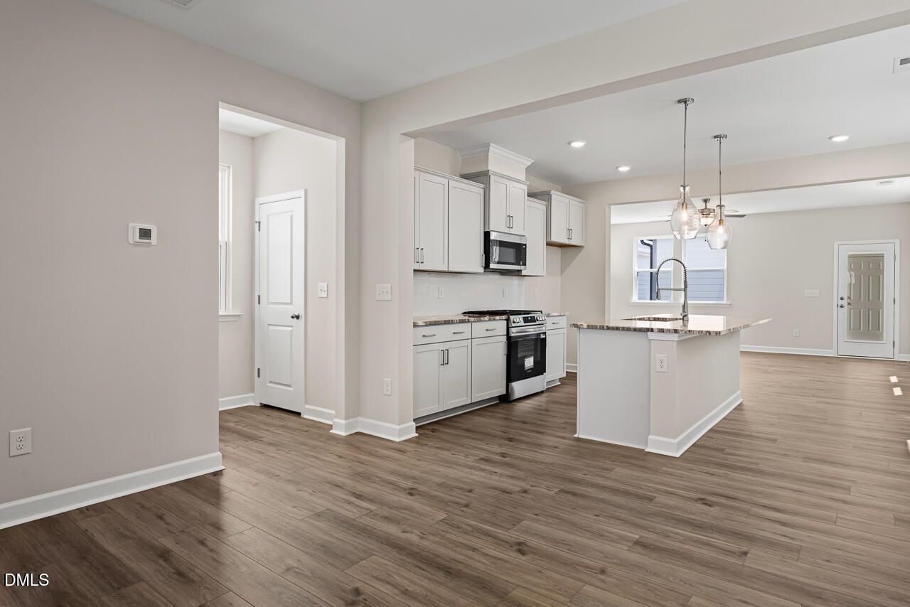 Open-concept kitchen with white cabinets and island in The Alexander C floor plan at Forestville Yard, Knightdale, NC.