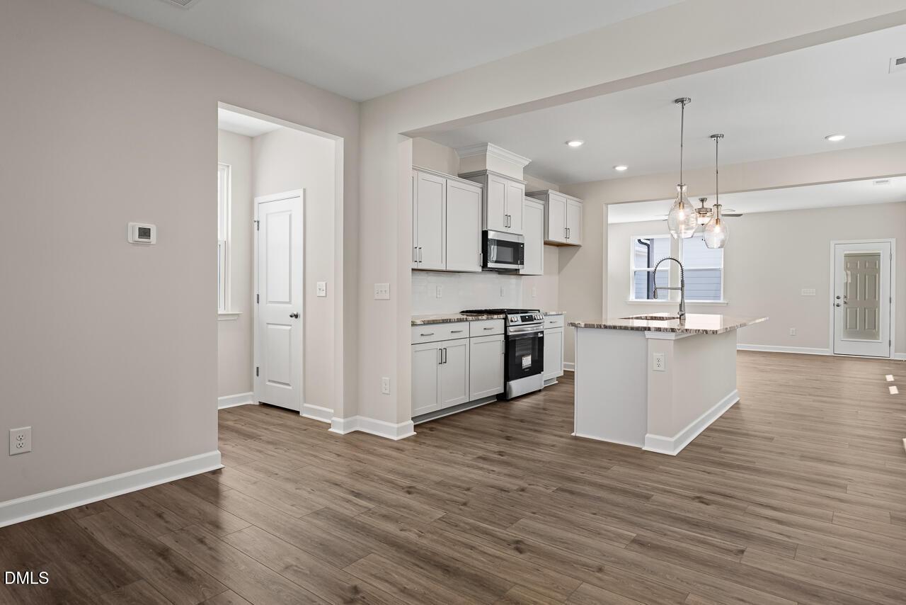 Open-concept kitchen with white cabinets and island in The Alexander C floor plan at Forestville Yard, Knightdale, NC.