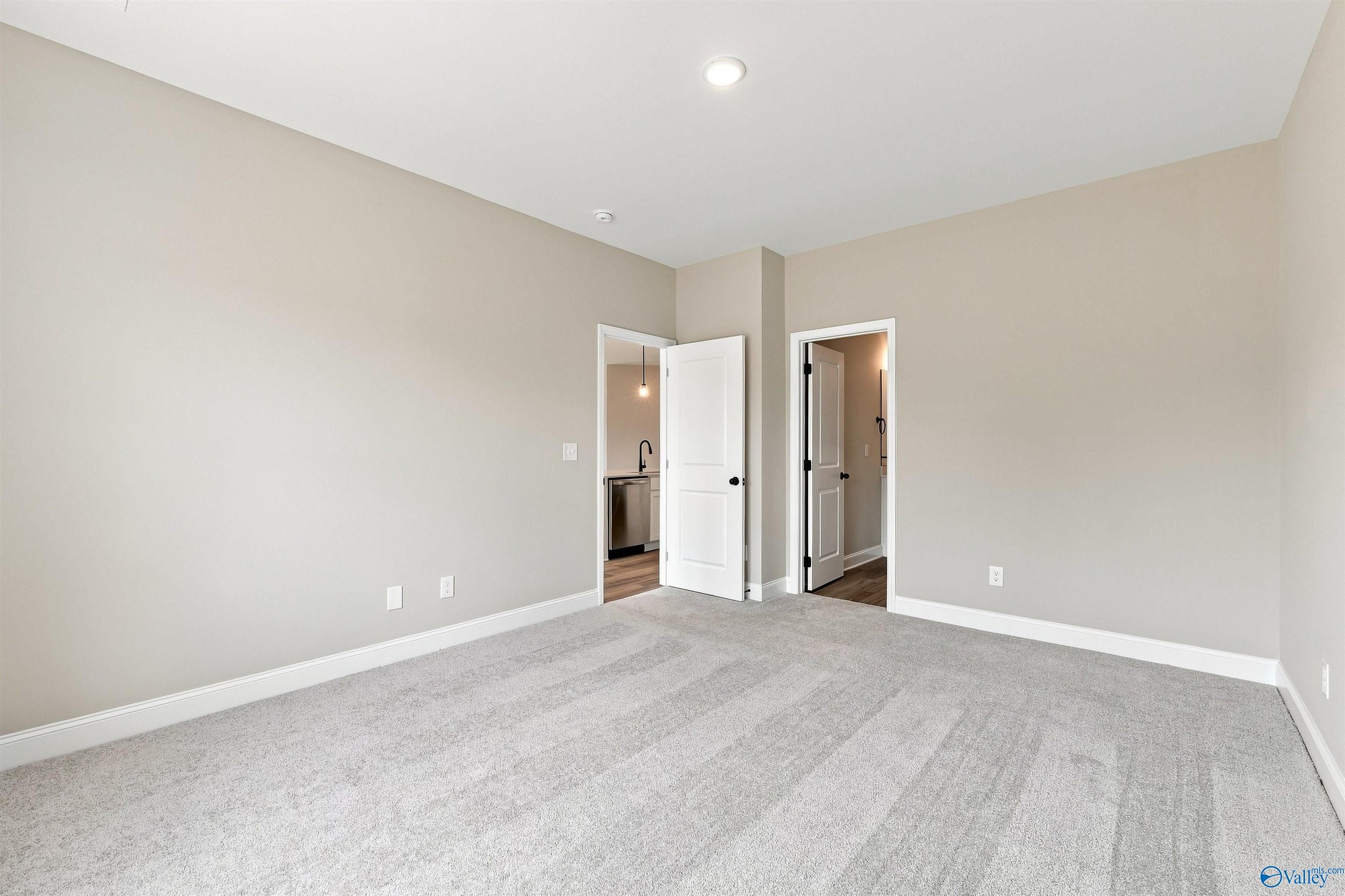 Spacious carpeted bedroom with neutral walls and white trim in Davidson Homes The Franklin C, Wood Trail, Toney, Alabama