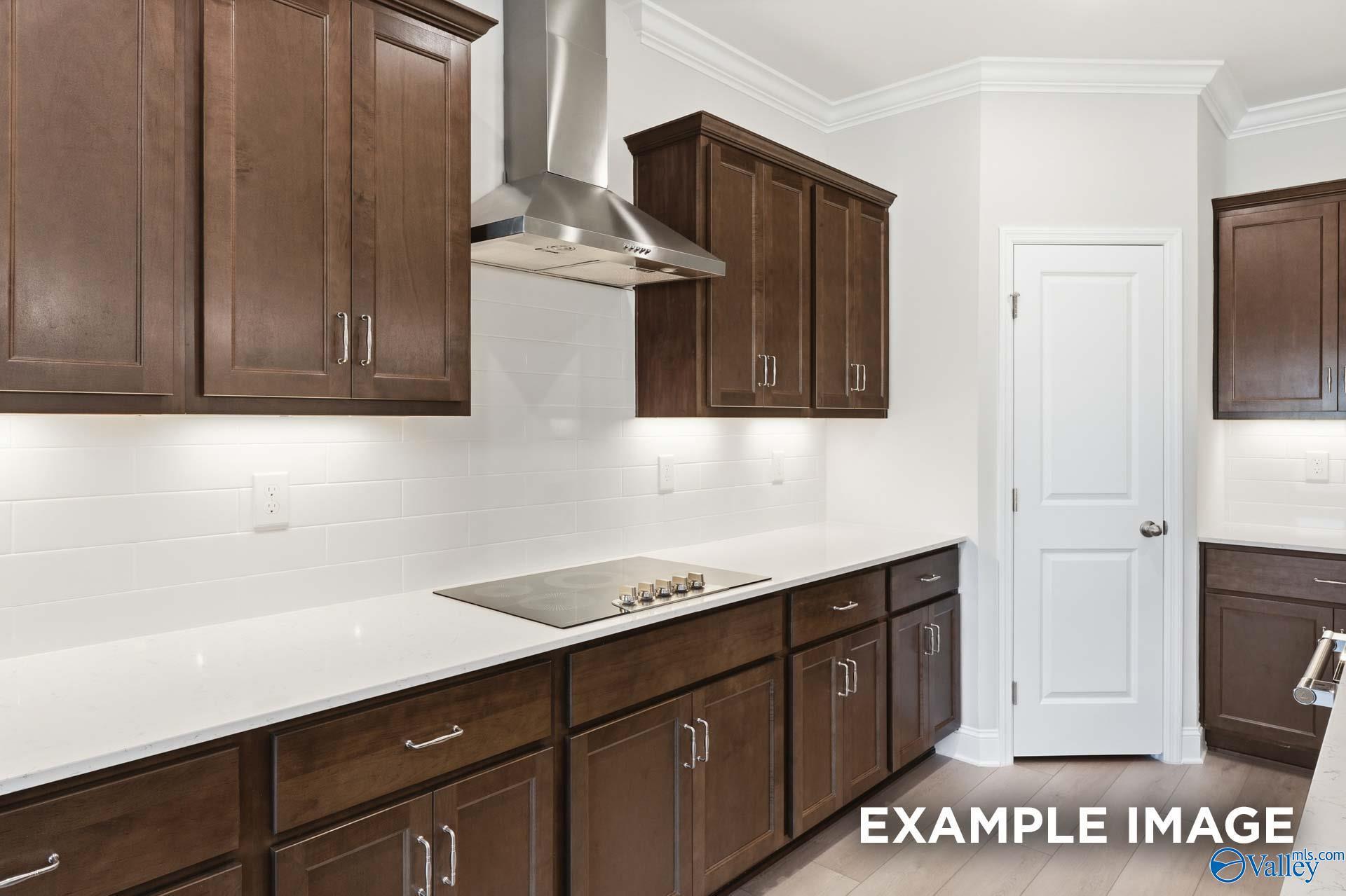 Modern kitchen with dark wood cabinets, white subway tile backsplash, quartz countertops in Davidson Homes Harrison D plan, Madison AL