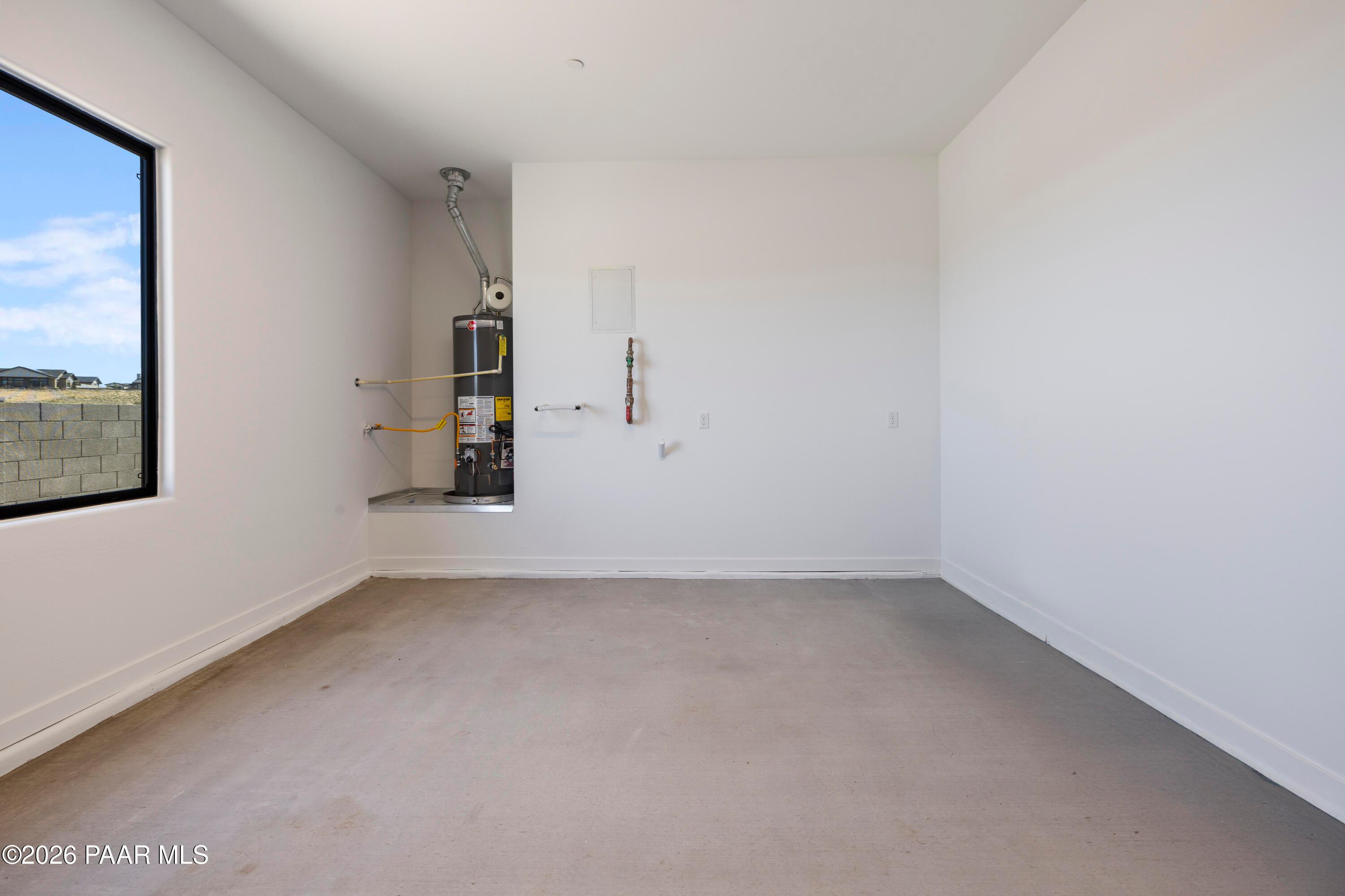 Spacious utility room with water heater, pipes, and large window in Davidson Homes The Soleil E, Hidden Hills, Prescott, Arizona
