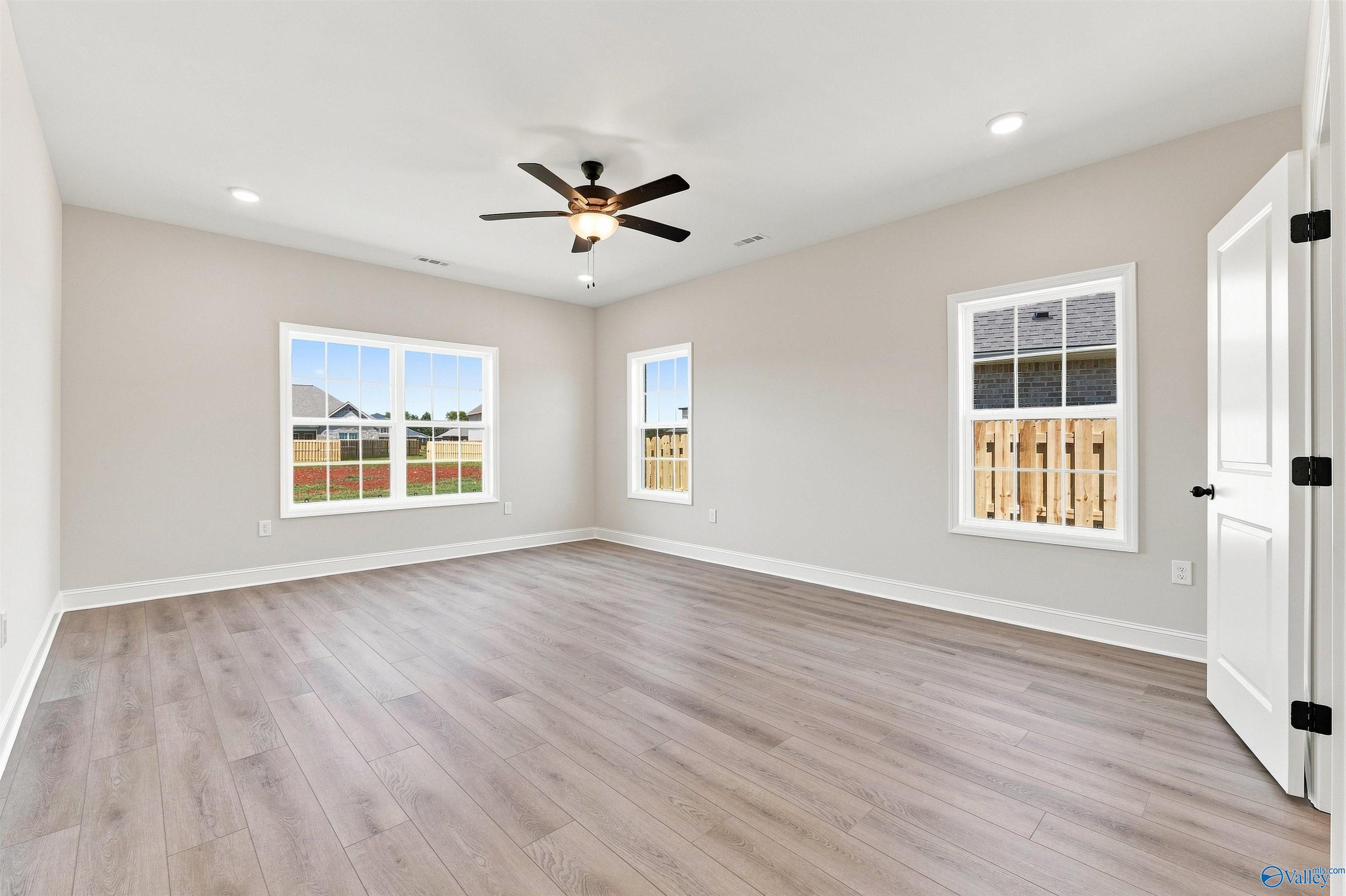 Spacious secondary bedroom with light wood-style flooring and ceiling fan in The Oxford floor plan, Kendall Farms, Toney, AL.