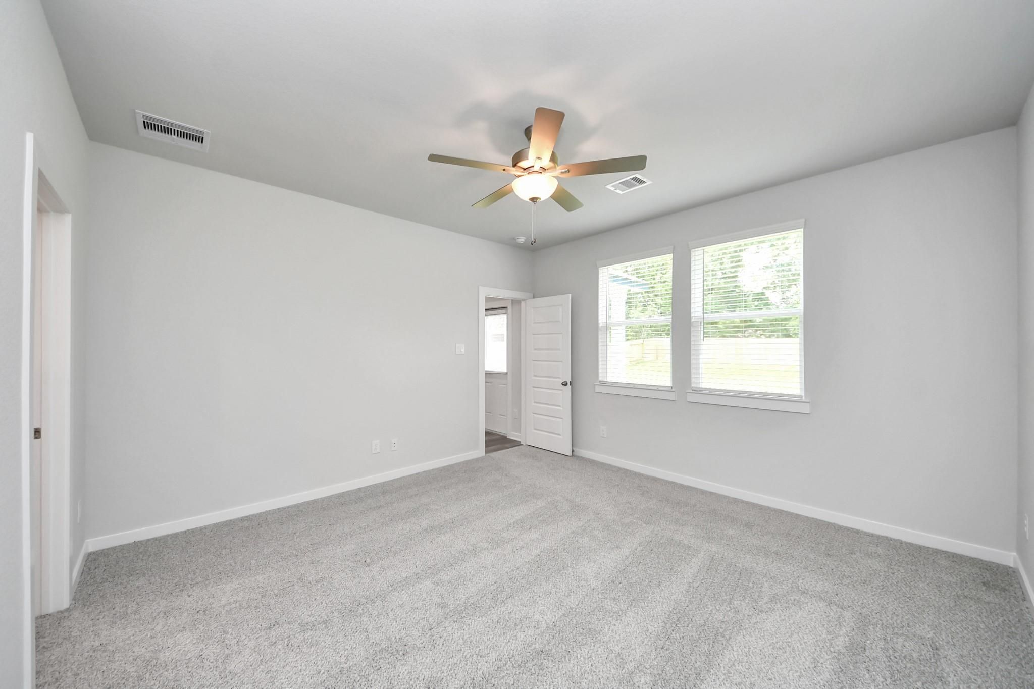 Spacious bedroom with carpet and ceiling fan in The Sabine E floor plan by Davidson Homes in Liberty Estates, Texas.