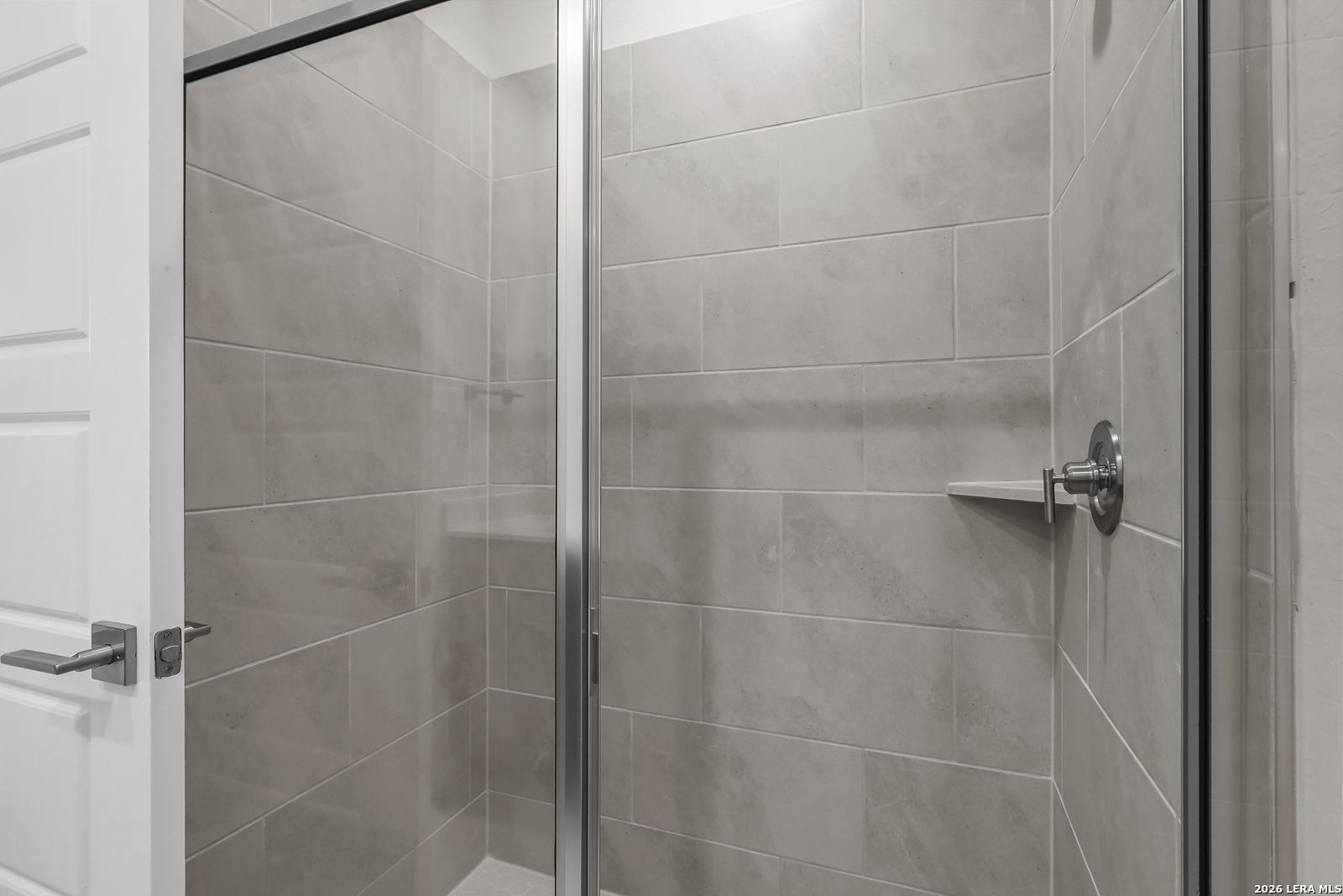 Modern walk-in shower with gray tile and glass door in a Davidson Homes San Marcos F floor plan, San Antonio, Texas.