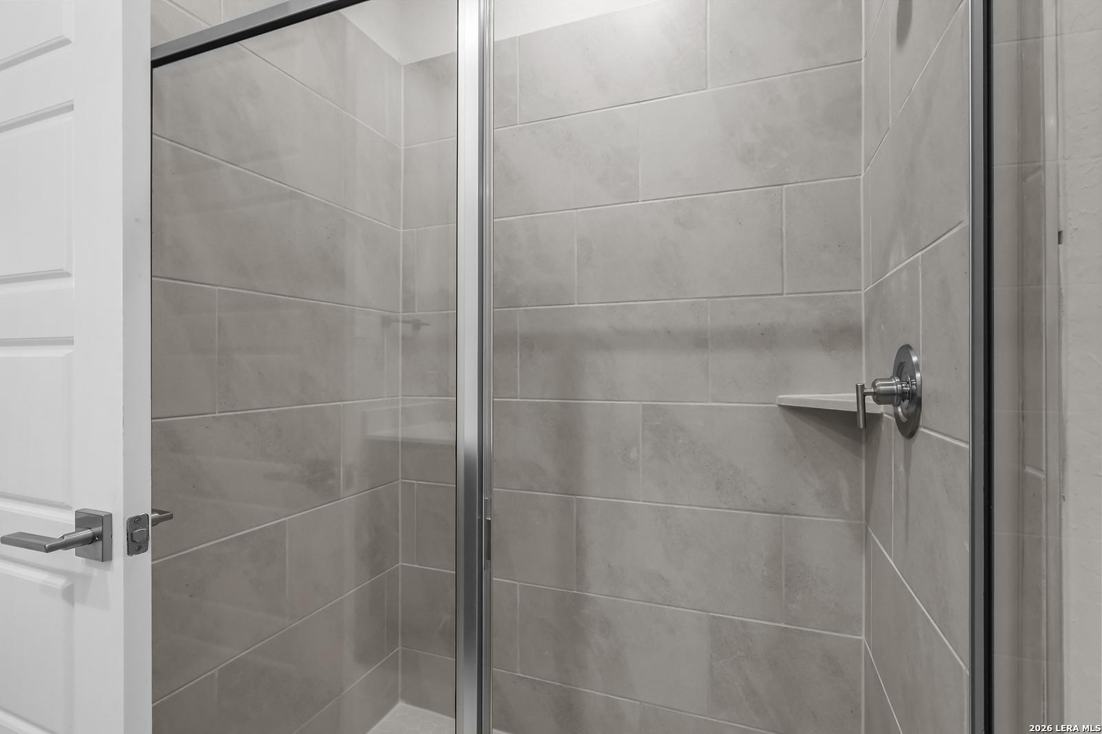 Modern walk-in shower with gray tile and glass door in a Davidson Homes San Marcos F floor plan, San Antonio, Texas.