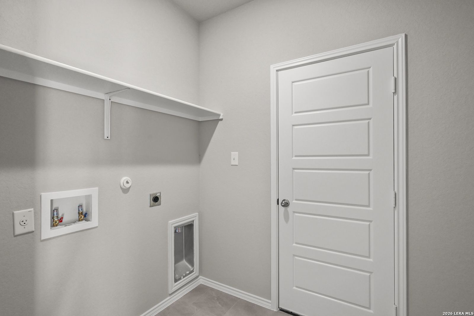 Modern laundry room with washer/dryer hookups, built-in shelves, and pet door in The Frio B home, Applewhite Meadows, San Antonio