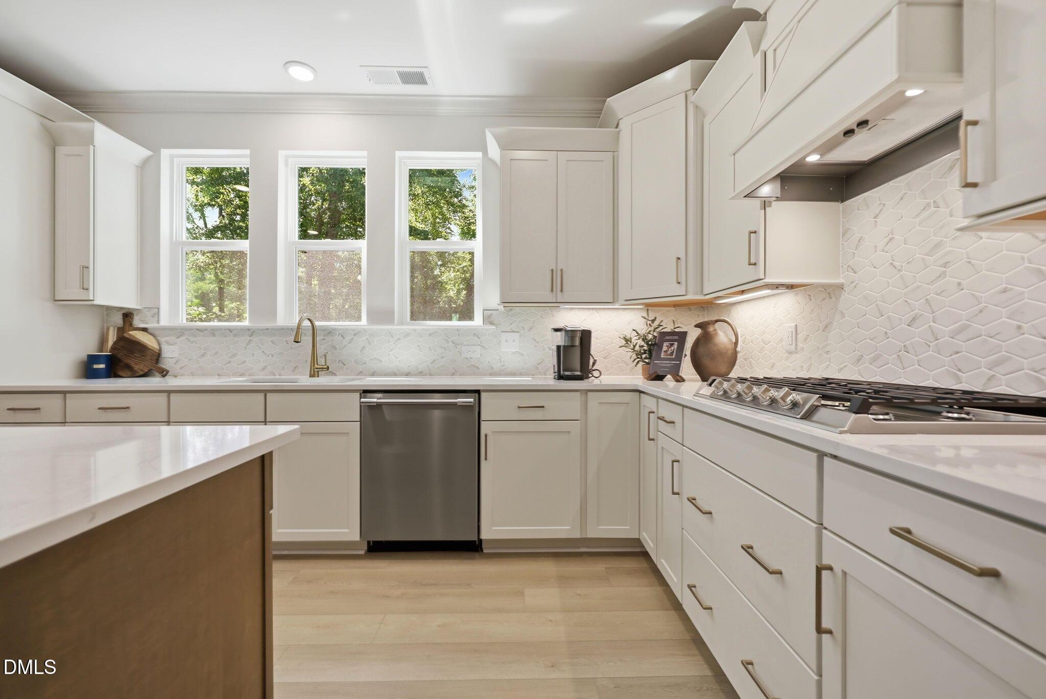Modern white kitchen with stainless steel appliances and quartz countertops in The Aspen B plan at Wendell Ridge, NC.