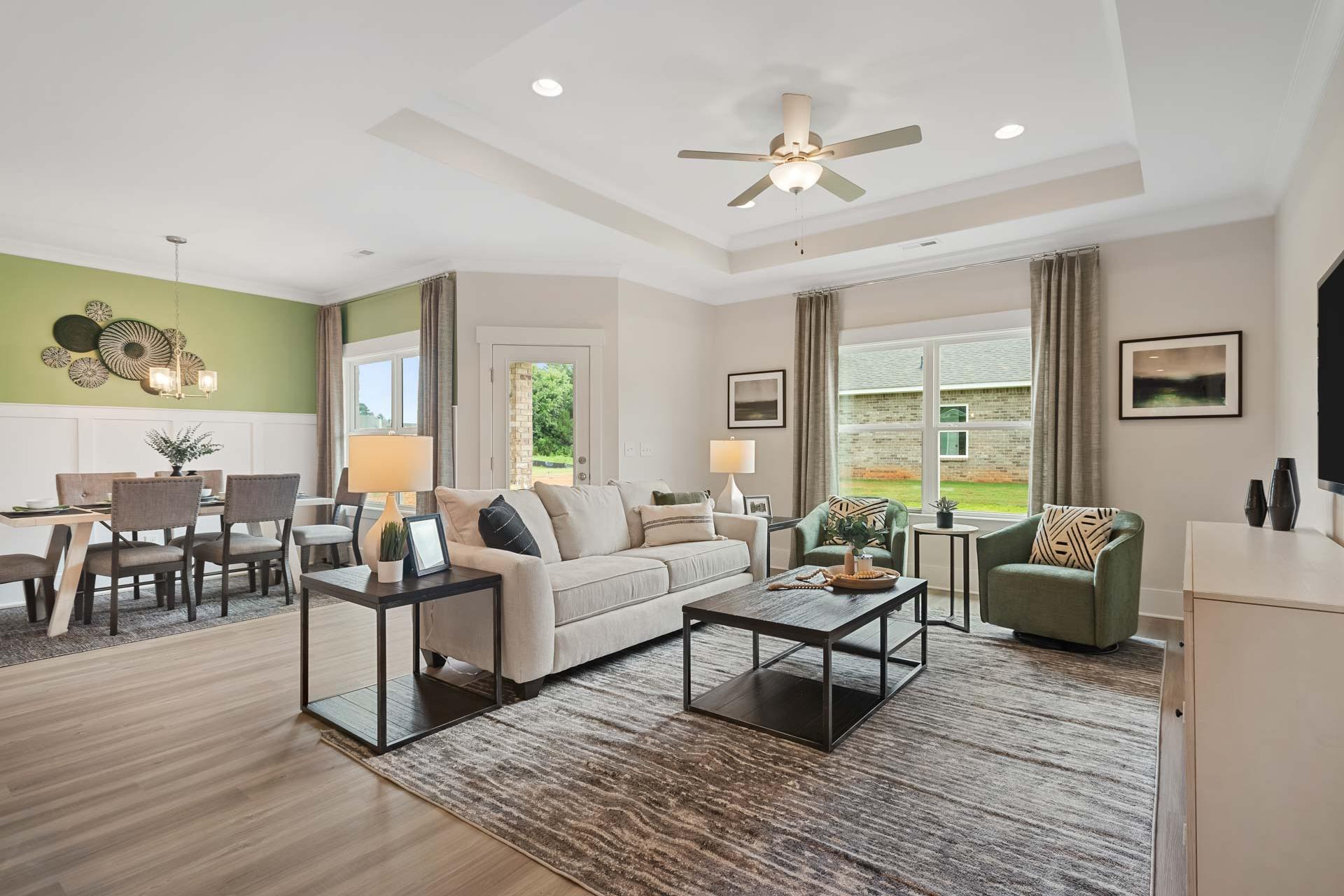 Spacious open-concept living dining room in Durham Farms Harvest Alabama with beige sofa neutral walls hardwood floors and large windows