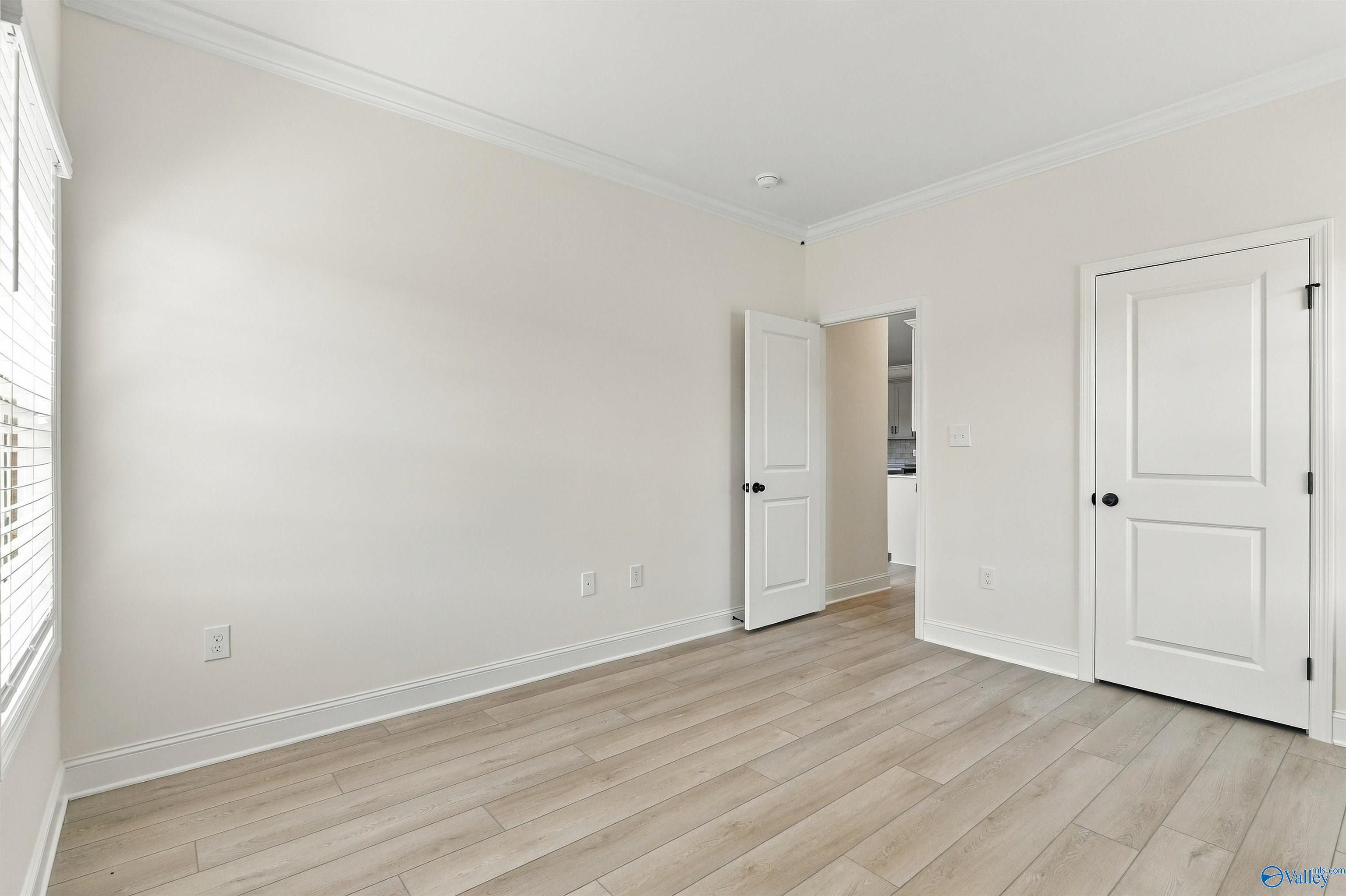 Bright bedroom with luxury vinyl plank flooring, crown molding, and white doors in Davidson Homes' The Valencia, Huntsville, AL