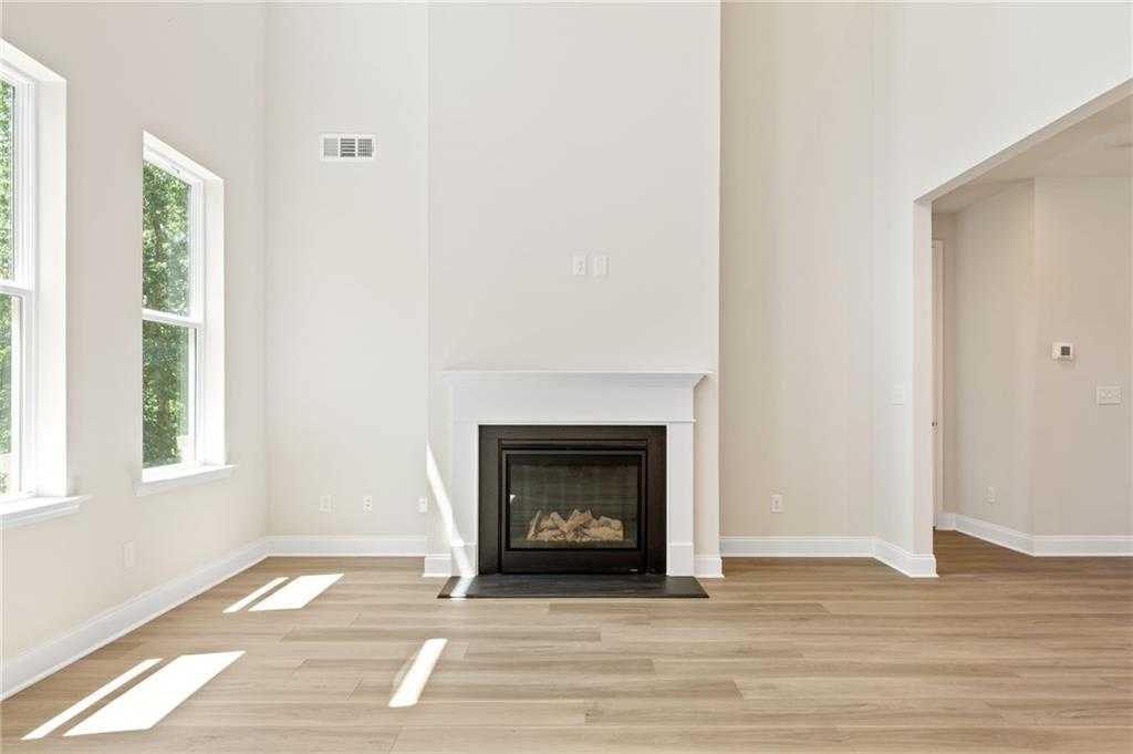 Cozy great room with white brick gas fireplace, hardwood floors, and large windows in Davidson Homes The Hampton C, Buford, GA